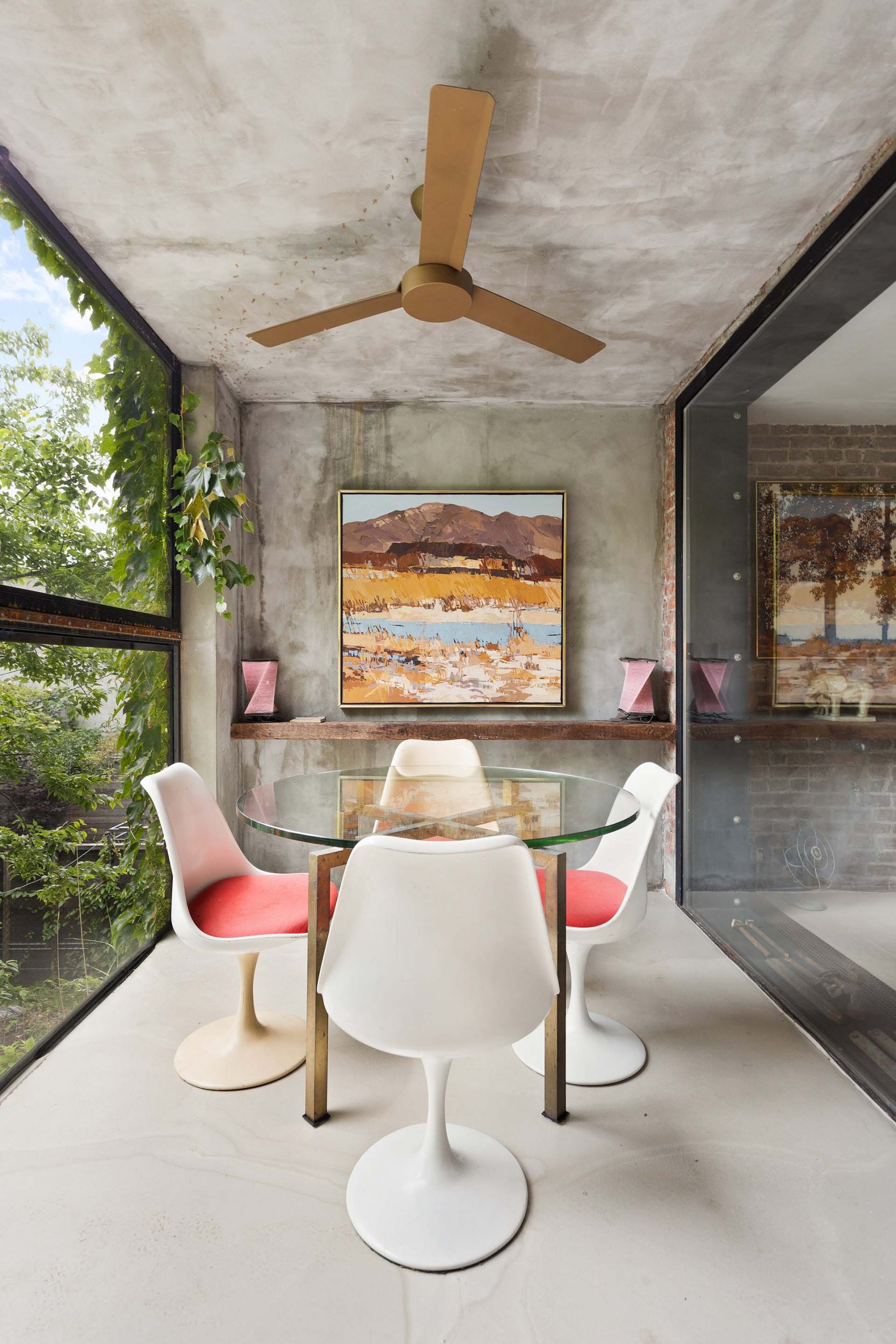 In this modern dining room, raw concrete wraps from the ceiling onto the wall and floor, while the glass walls allow natural light to filter through to the interior of the home.