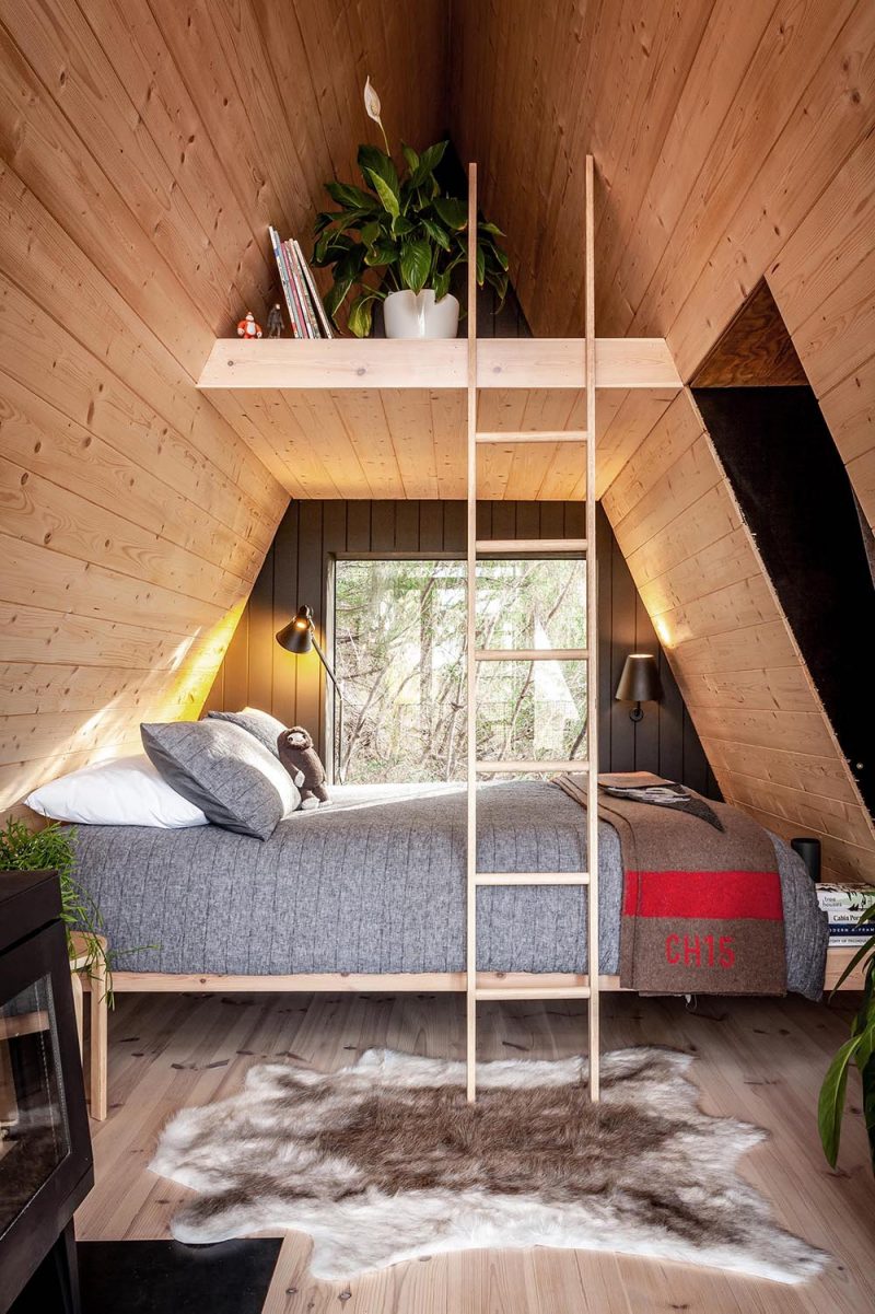 A Small Black A-Frame Cabin With A Wood Interior Was Designed As A