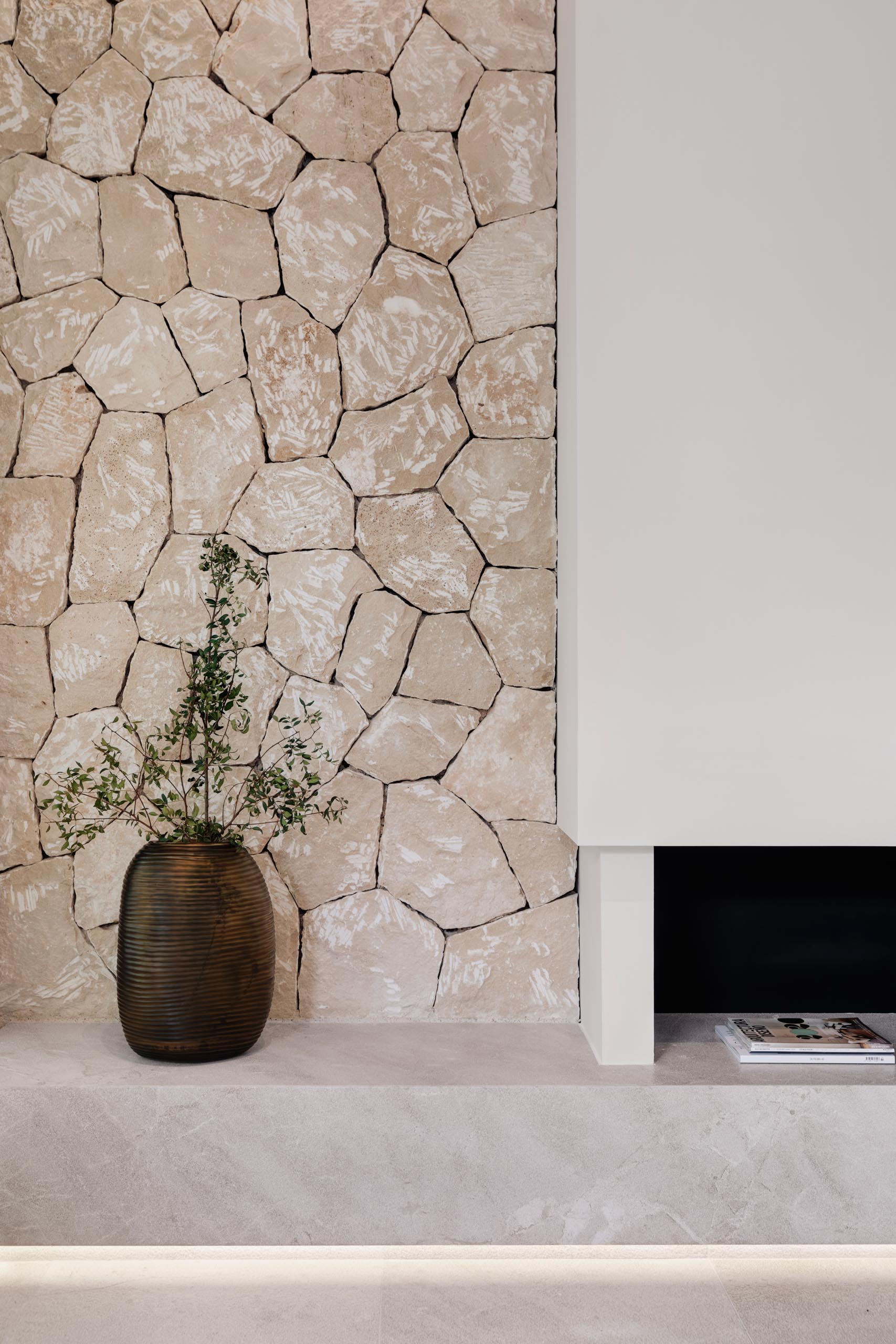 A stone wall and hidden lighting are unique design elements of this modern living room.