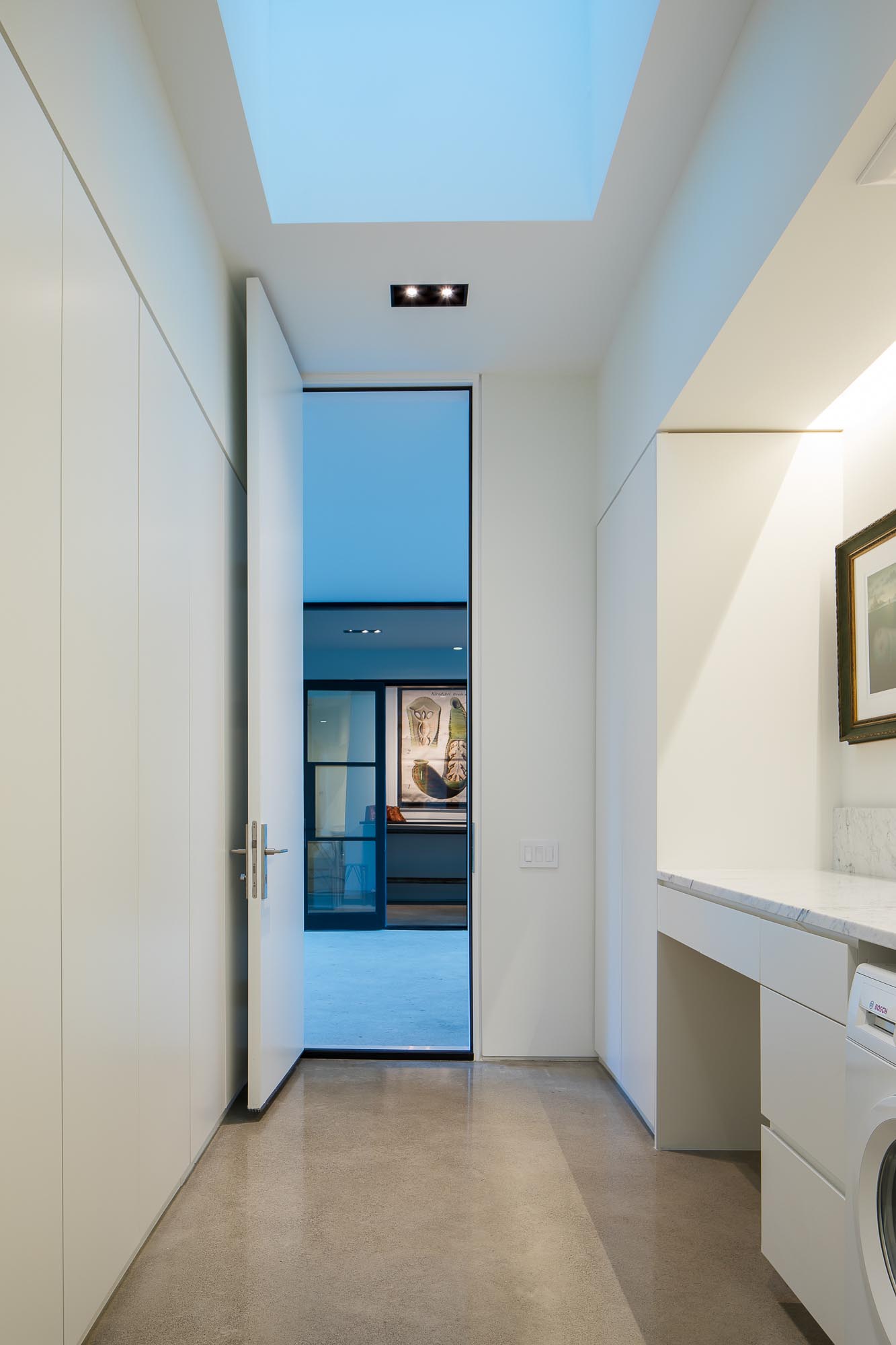 A modern white laundry room with concrete floors.