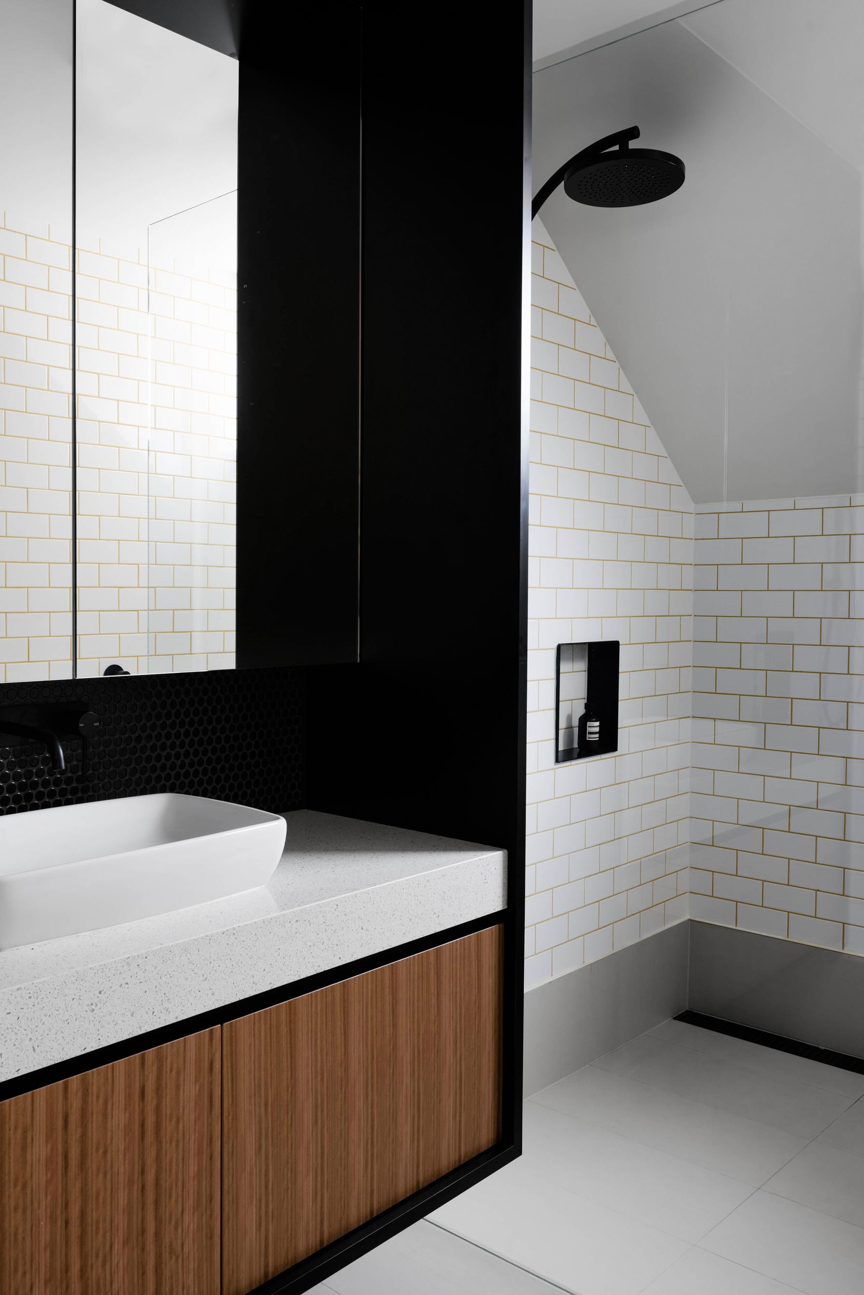 This modern bathroom has a black mirror/vanity surround and black-lined shower niche.