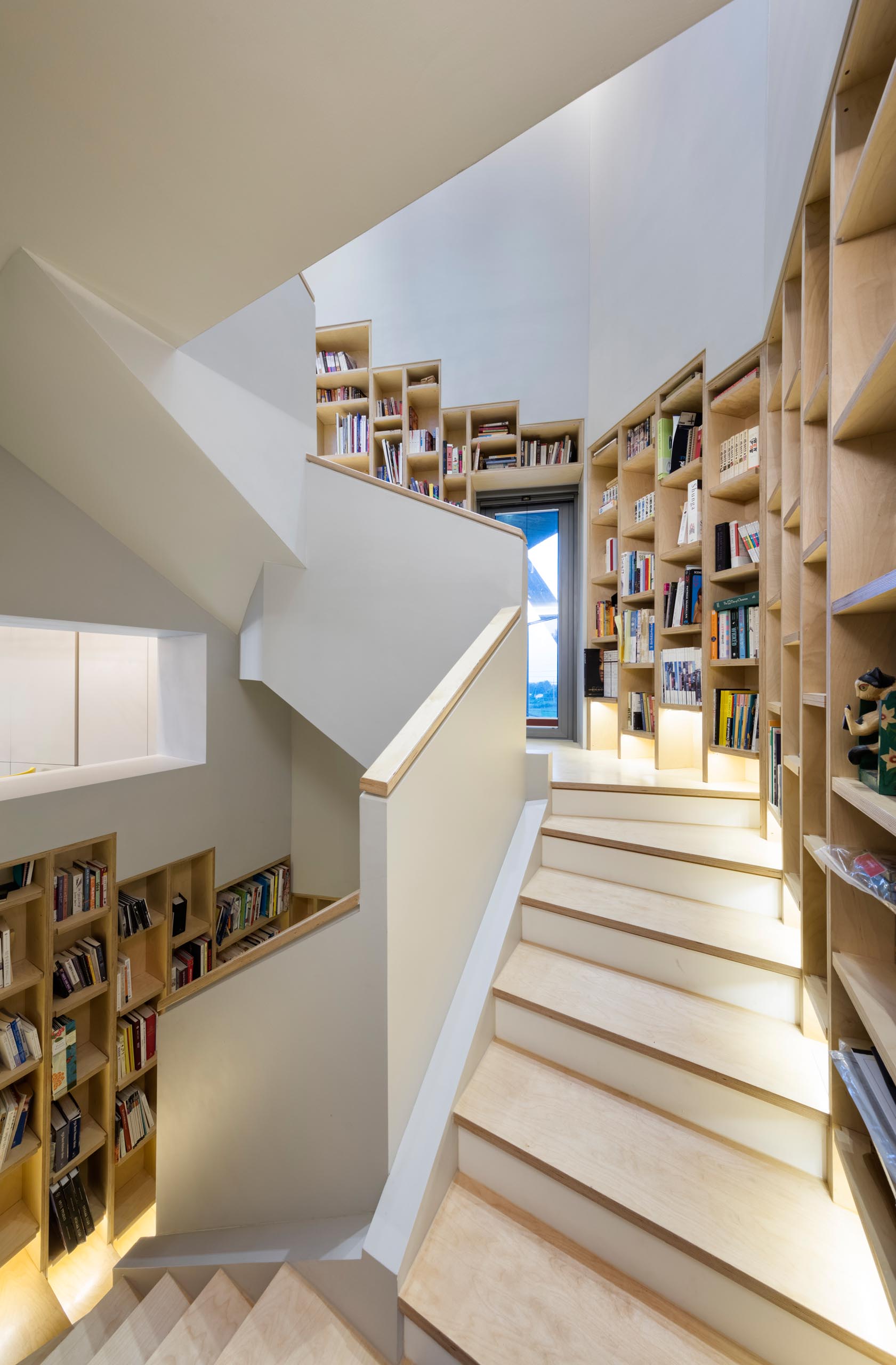 A built-in bookshelf that follows the staircase in a modern home.