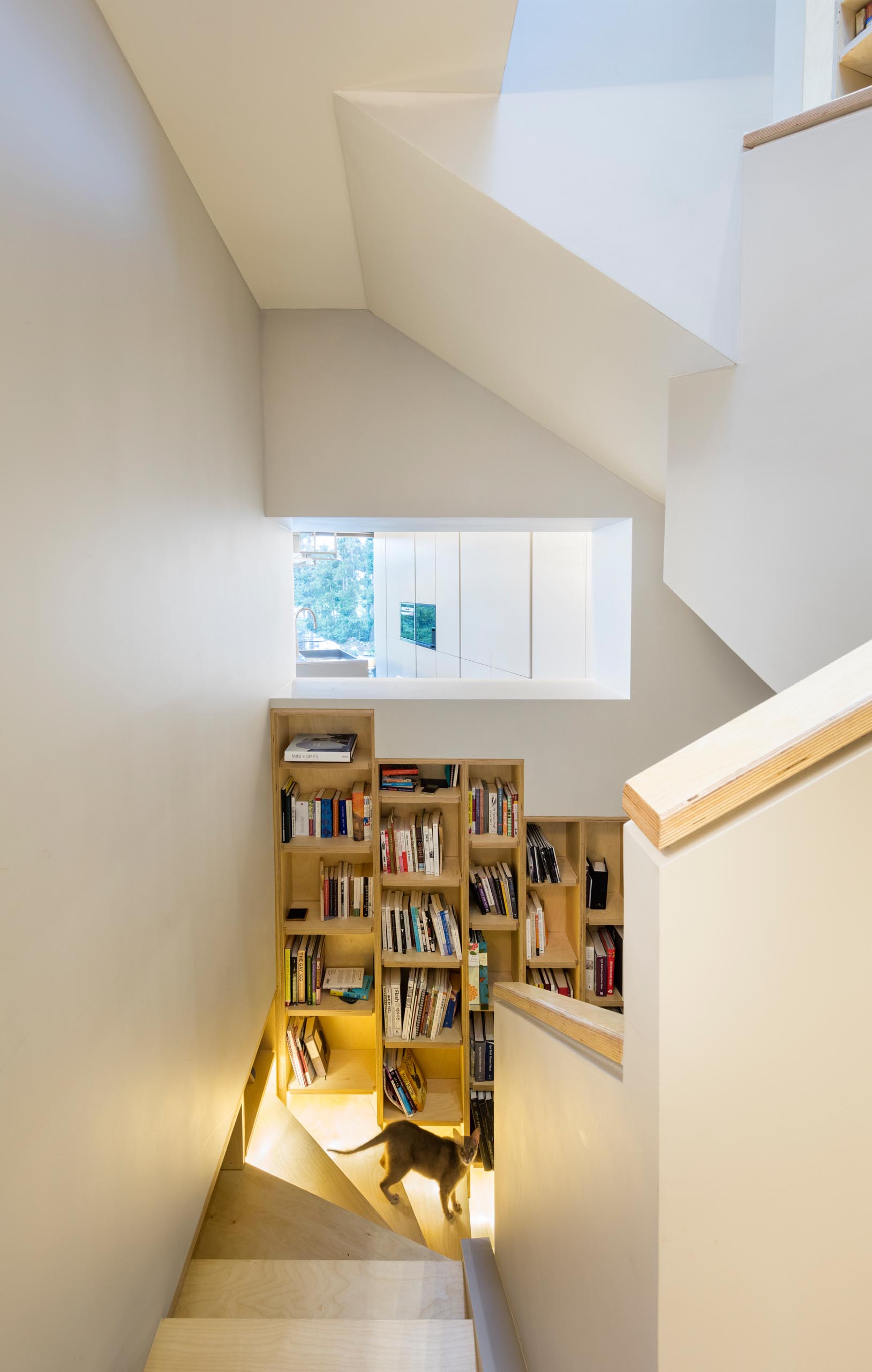 A built-in bookshelf lined with wood that follows the staircase in a modern home.