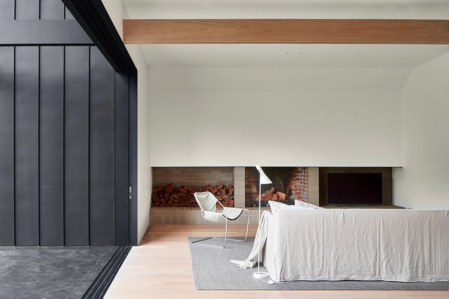 A living room with a modern brick fireplace and firewood storage.