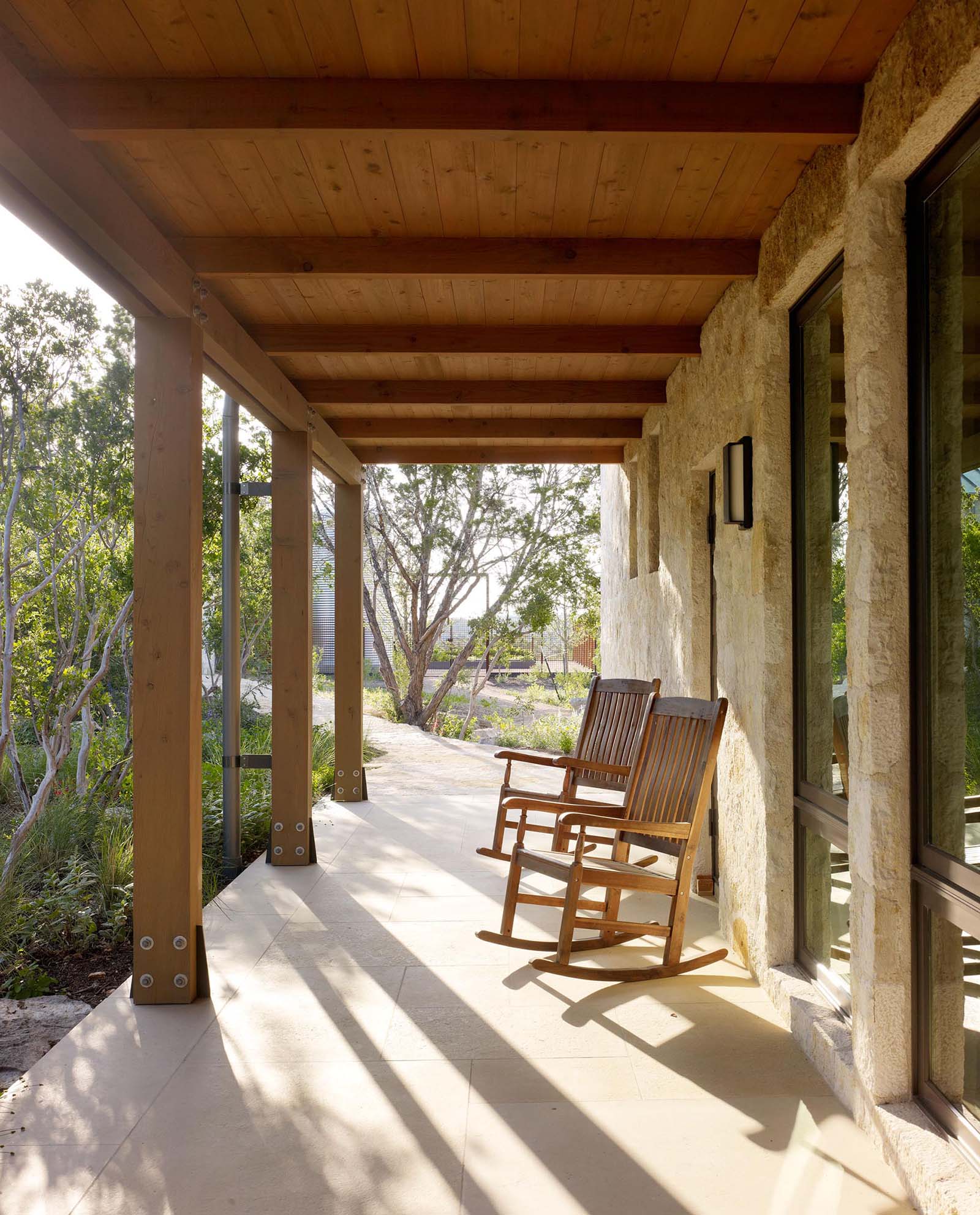 A covered porch by a limestone wall.