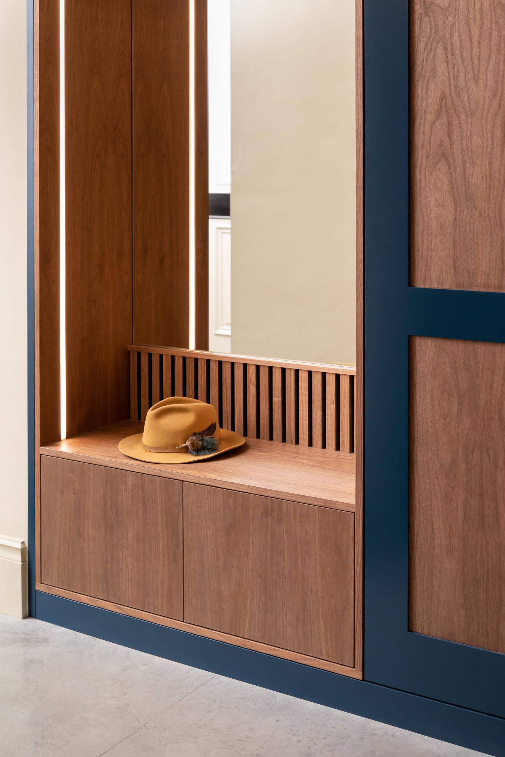 A modern custom designed entryway bench with a mirror, storage, and integrated LED lighting.