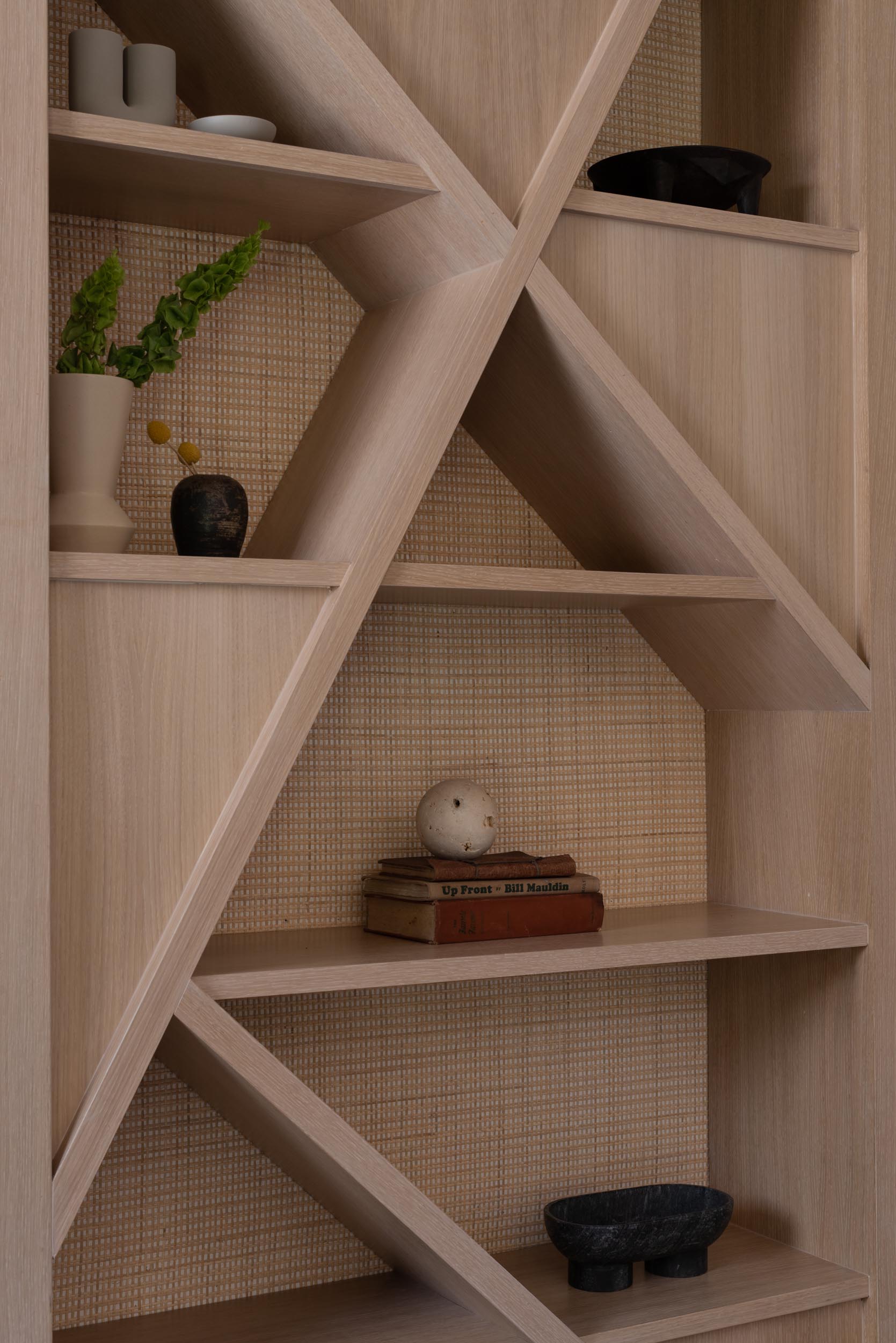 A modern shelving unit with a natural cane backing.