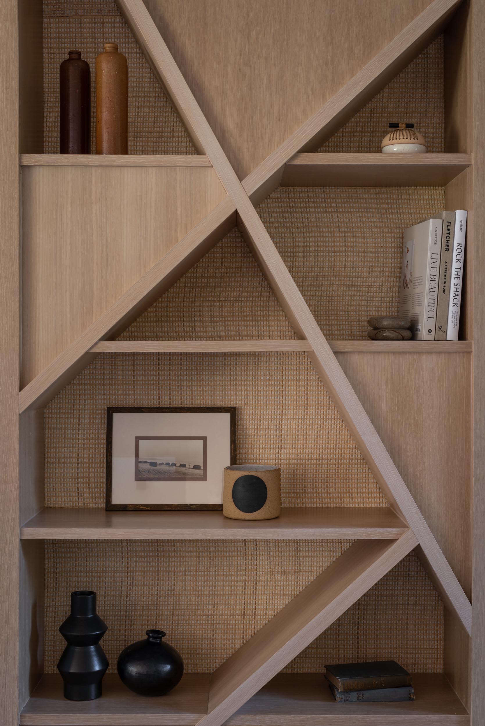 A modern wood shelving unit with a natural cane backing.