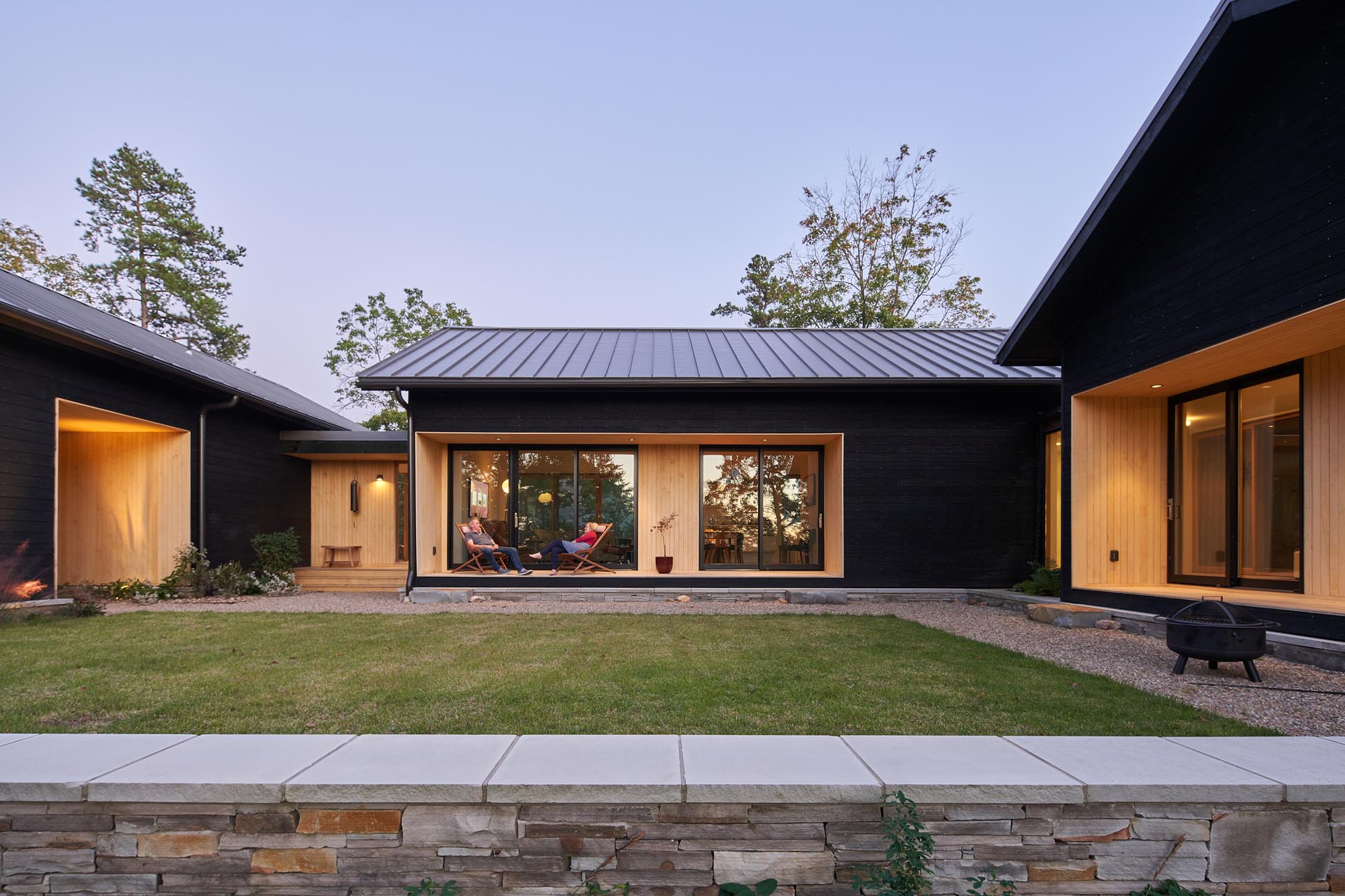 A modern home with burnt wood siding and alcoves lined with contrasting light wood.