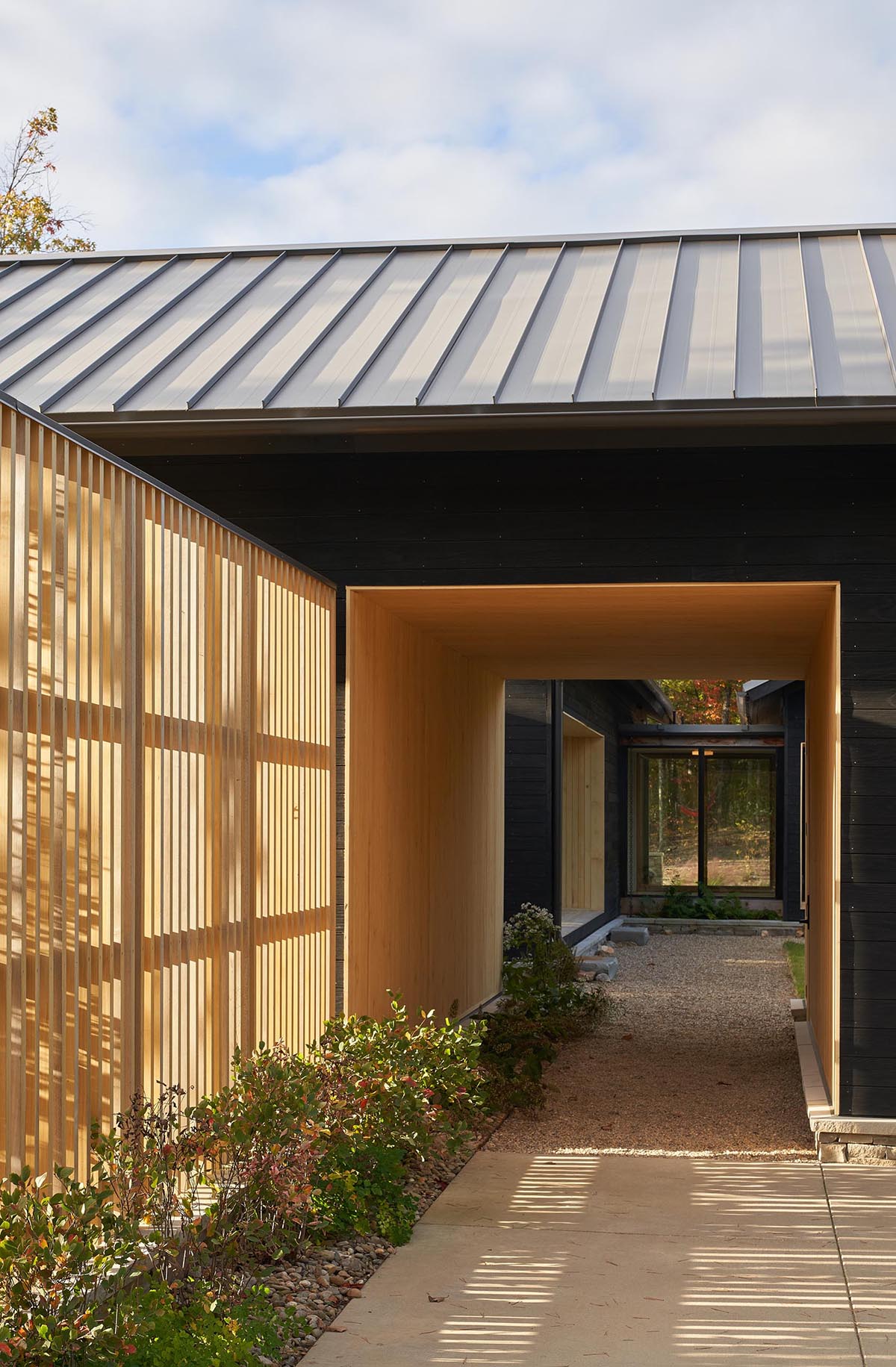 A modern home with burnt wood siding and alcoves lined with contrasting light wood.