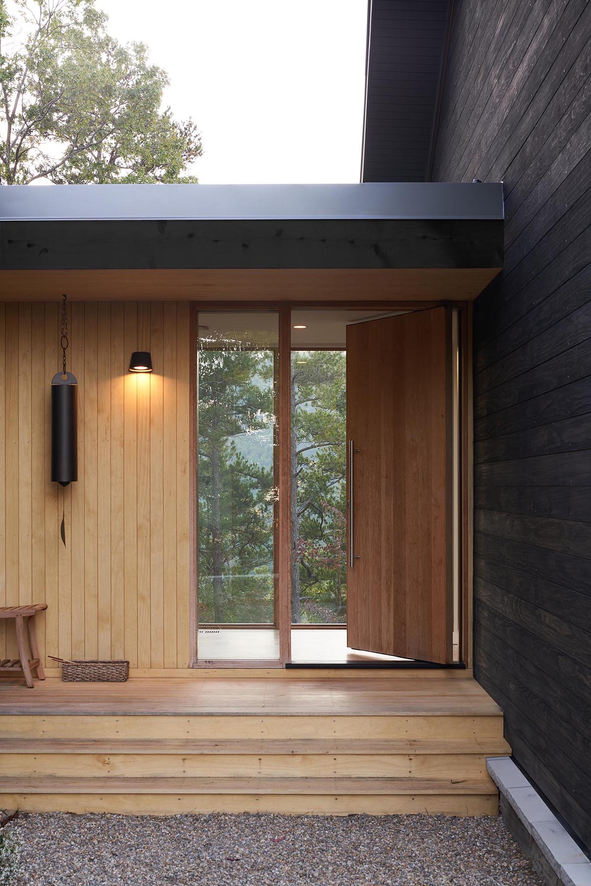 A modern home with burnt wood siding and alcoves lined with contrasting light wood.