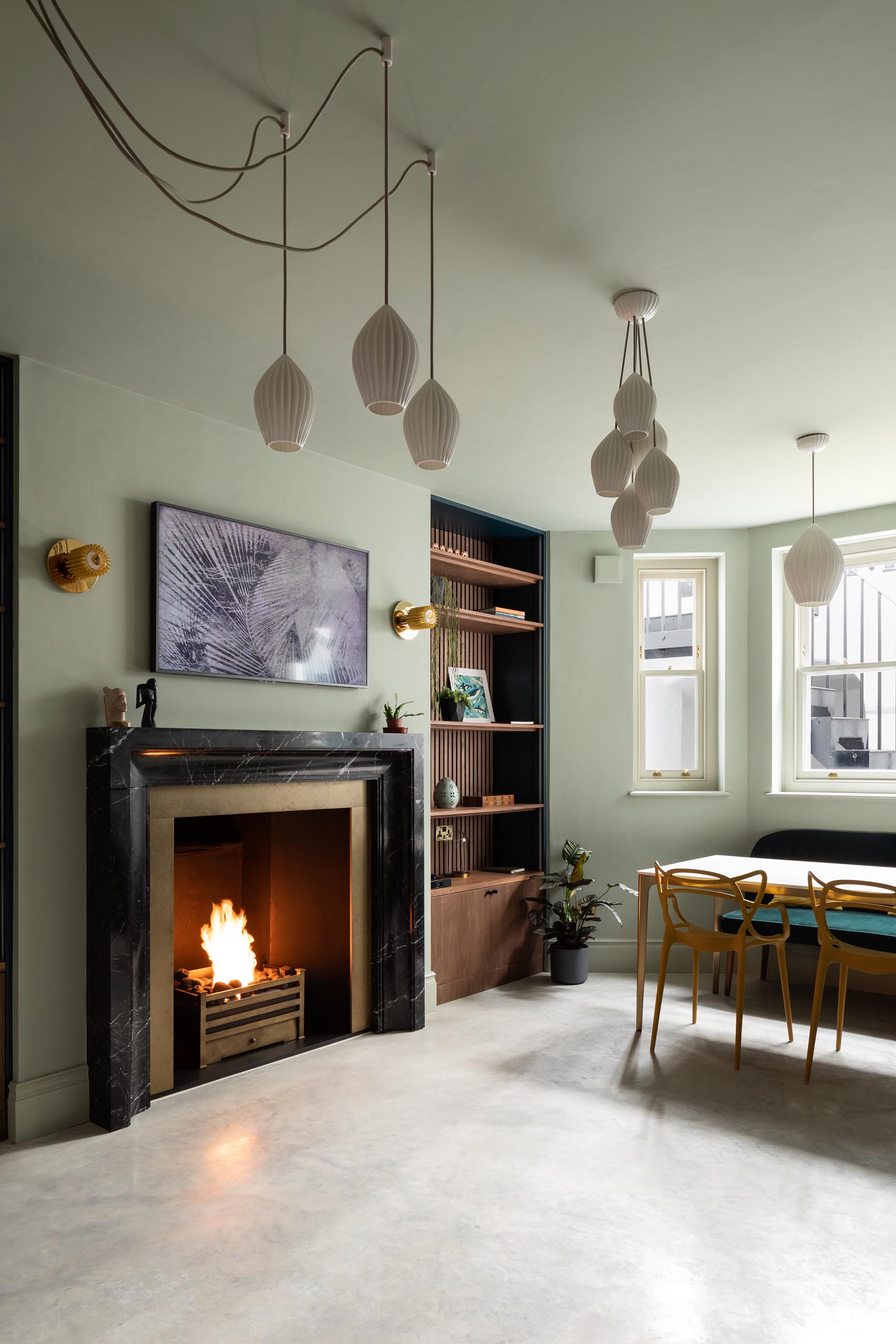 White lighting hangs from the ceiling, while a fireplace is flanked with floor-to-ceiling wood bookshelves.