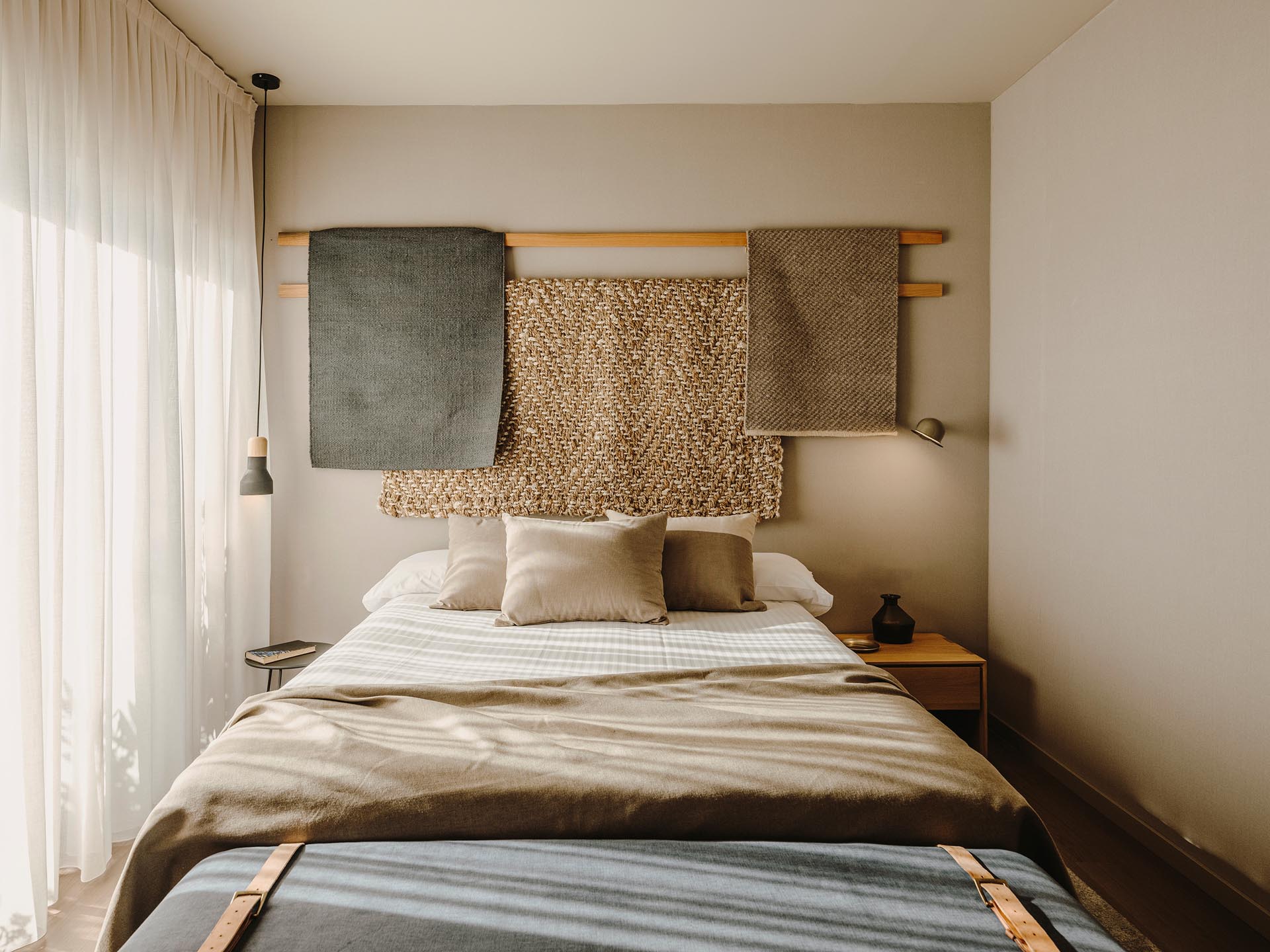 Wood lengths with draped fabric creates a unique wall decor installation in a bedroom