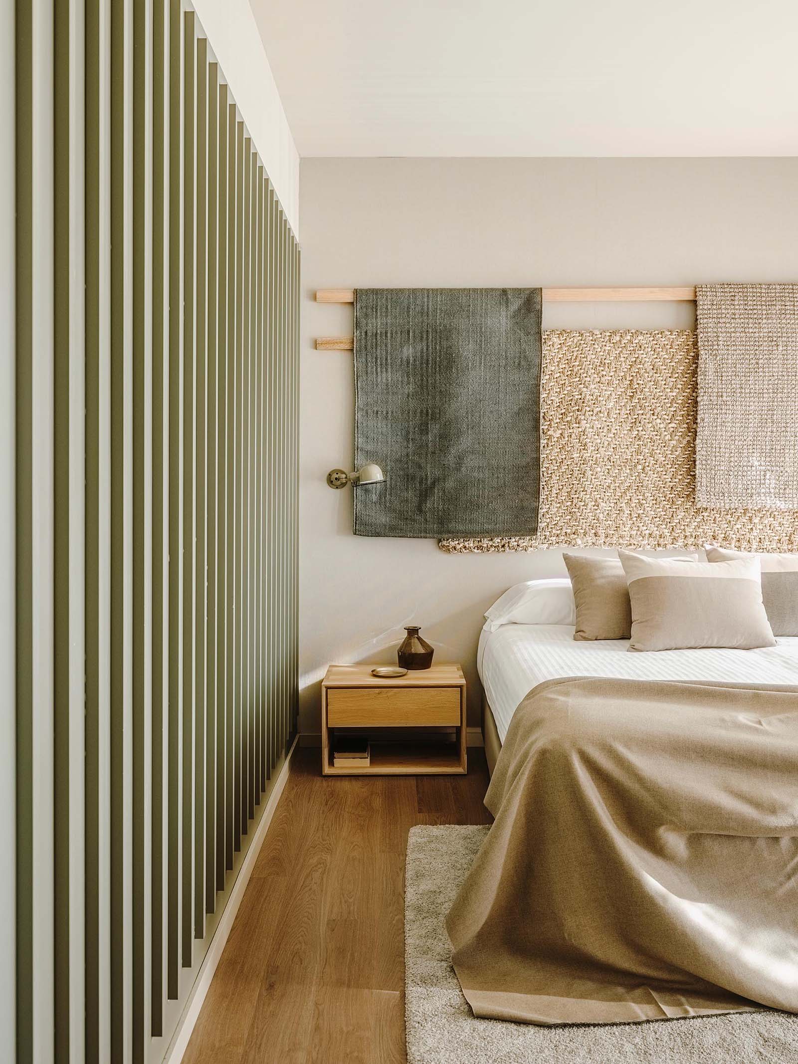 Wood lengths with draped fabric creates a unique wall decor installation in a bedroom