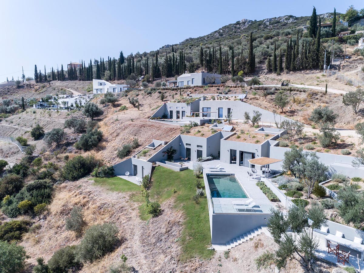 A trio of modern houses built into the hillside have multiple green roofs to help it blend in.