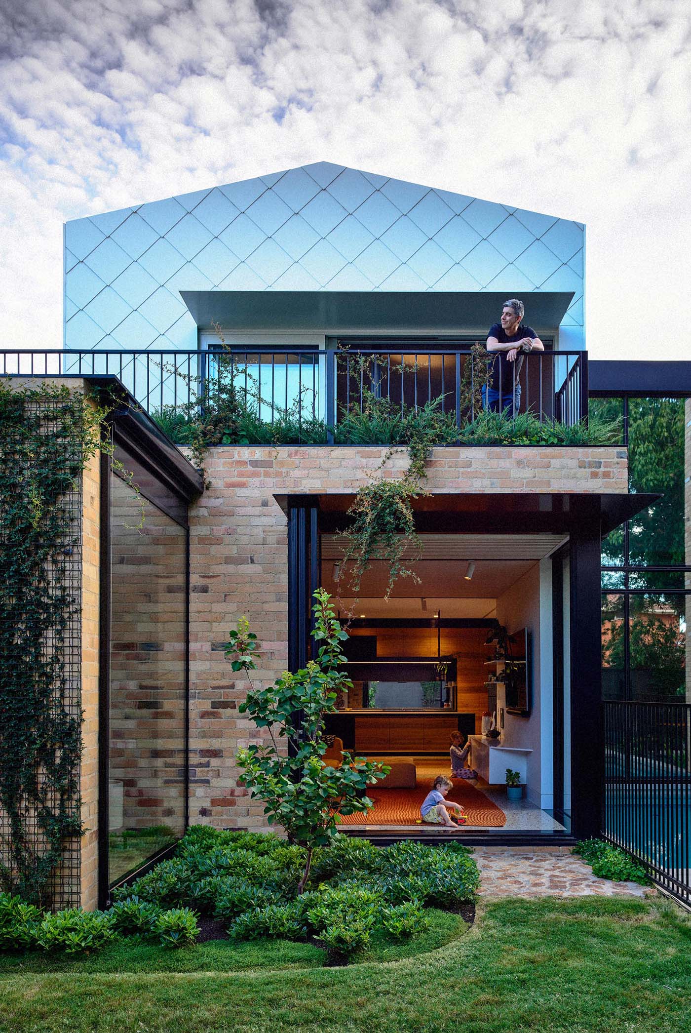 A modern home with indoor/outdoor living spaces, has been built using recycled yellow brick and metal shingles.