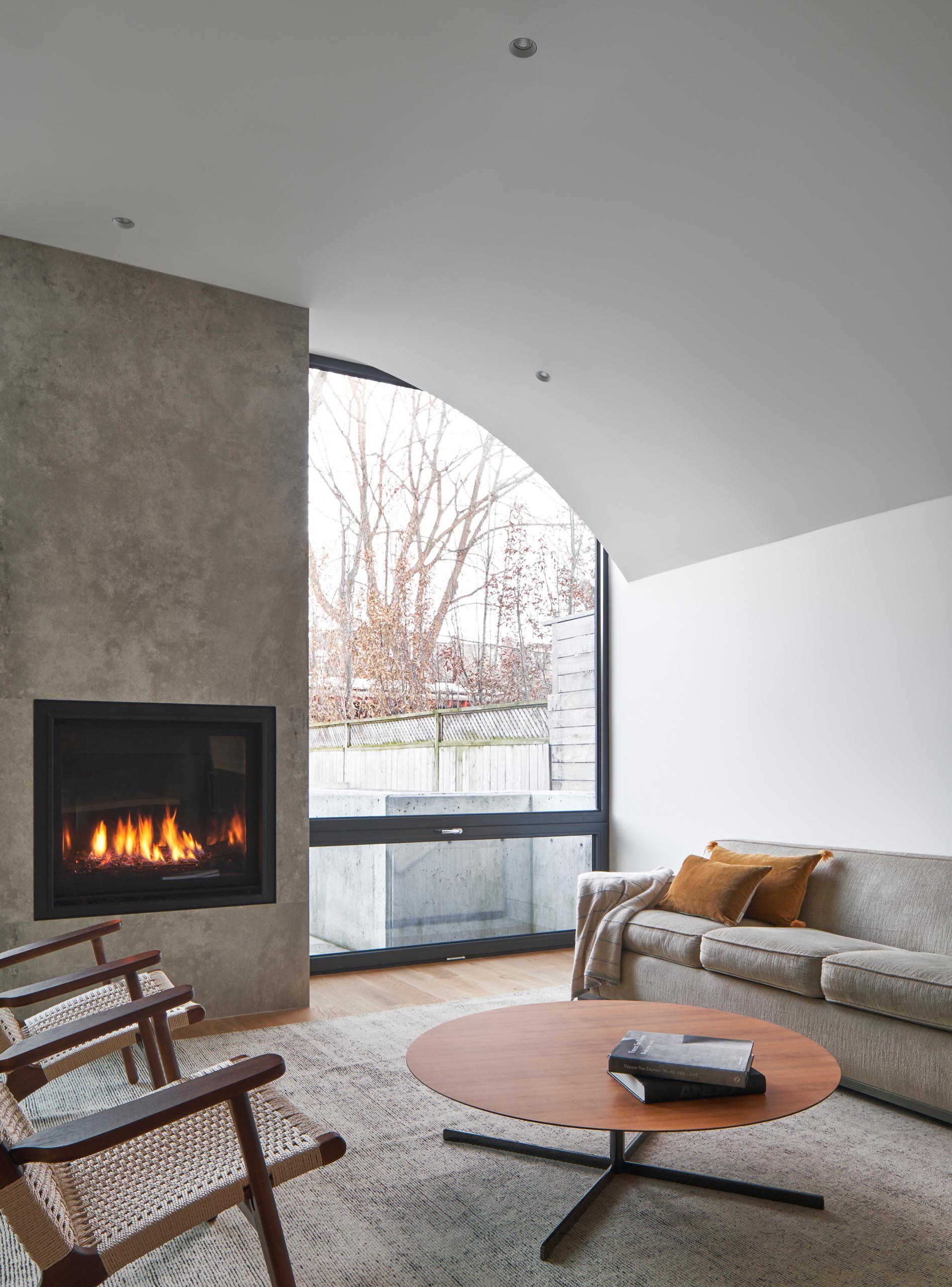 This modern living room, which is located at the rear of the home, has a fireplace and a large window that provides a view of the backyard.