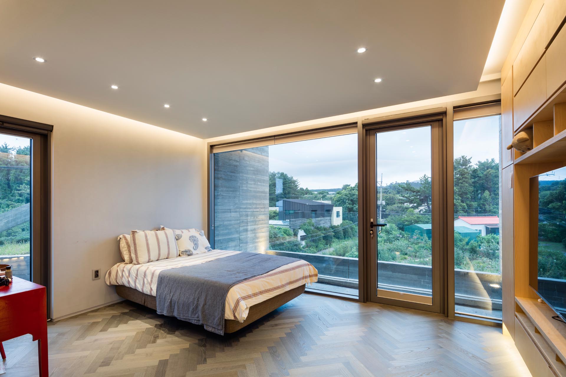 A minimalist bedroom with hidden lighting and large windows.