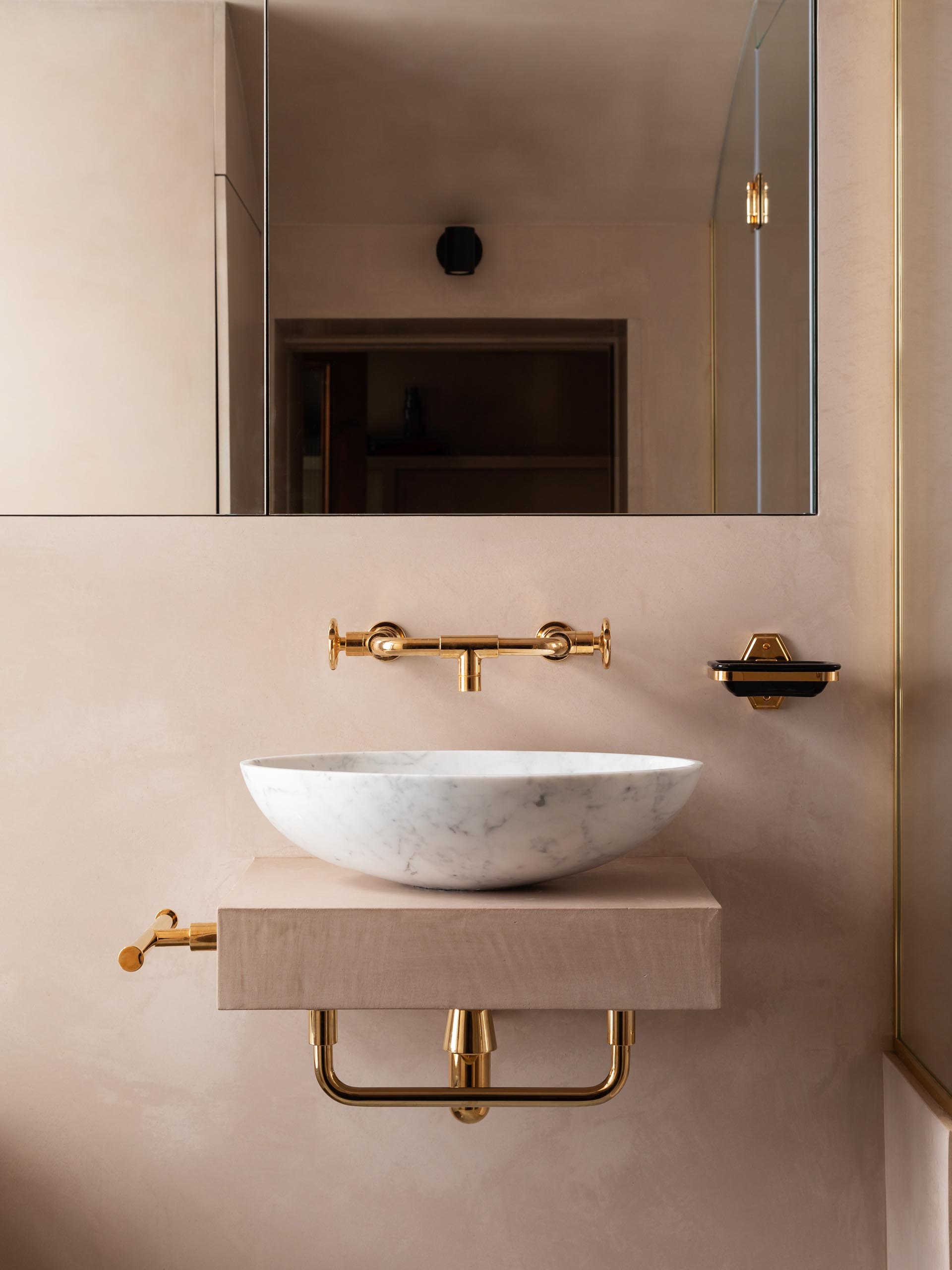 A blush pink bathroom with a marble vessel sink and rose gold hardware.