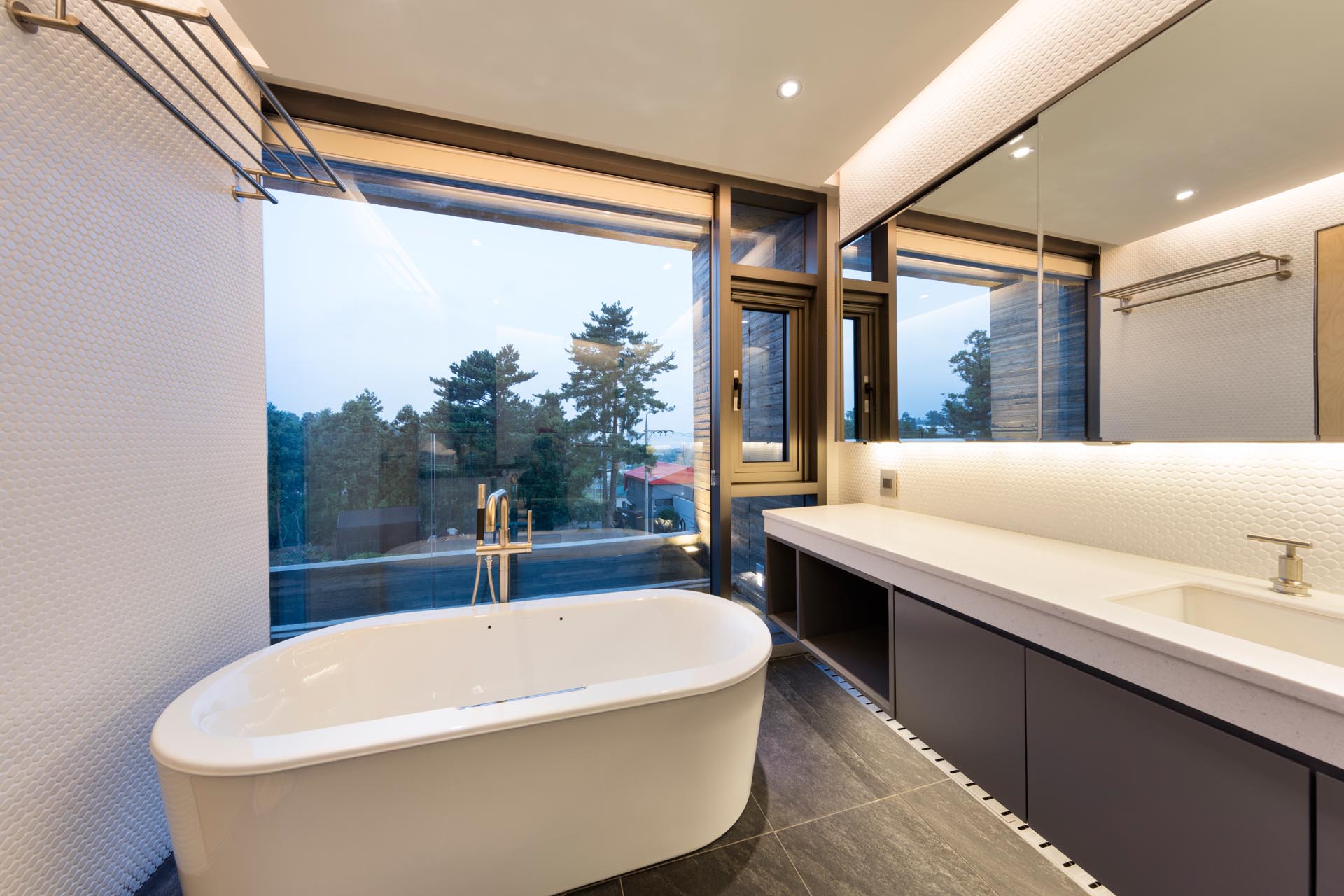 A modern bathroom with a freestanding bathtub and a large picture window.