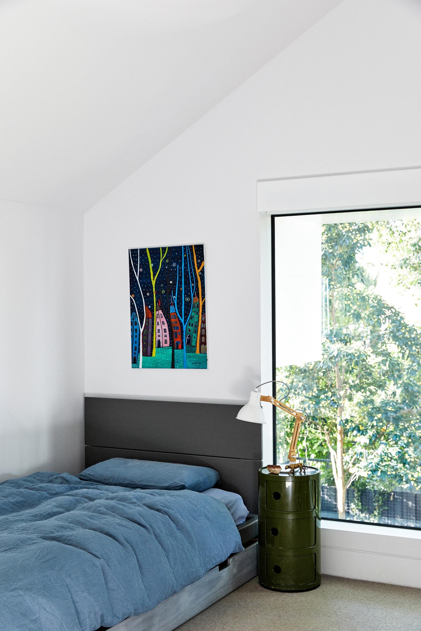 In this modern bedroom, bright white walls create a clean and crisp look, while the artwork adds a touch of color.