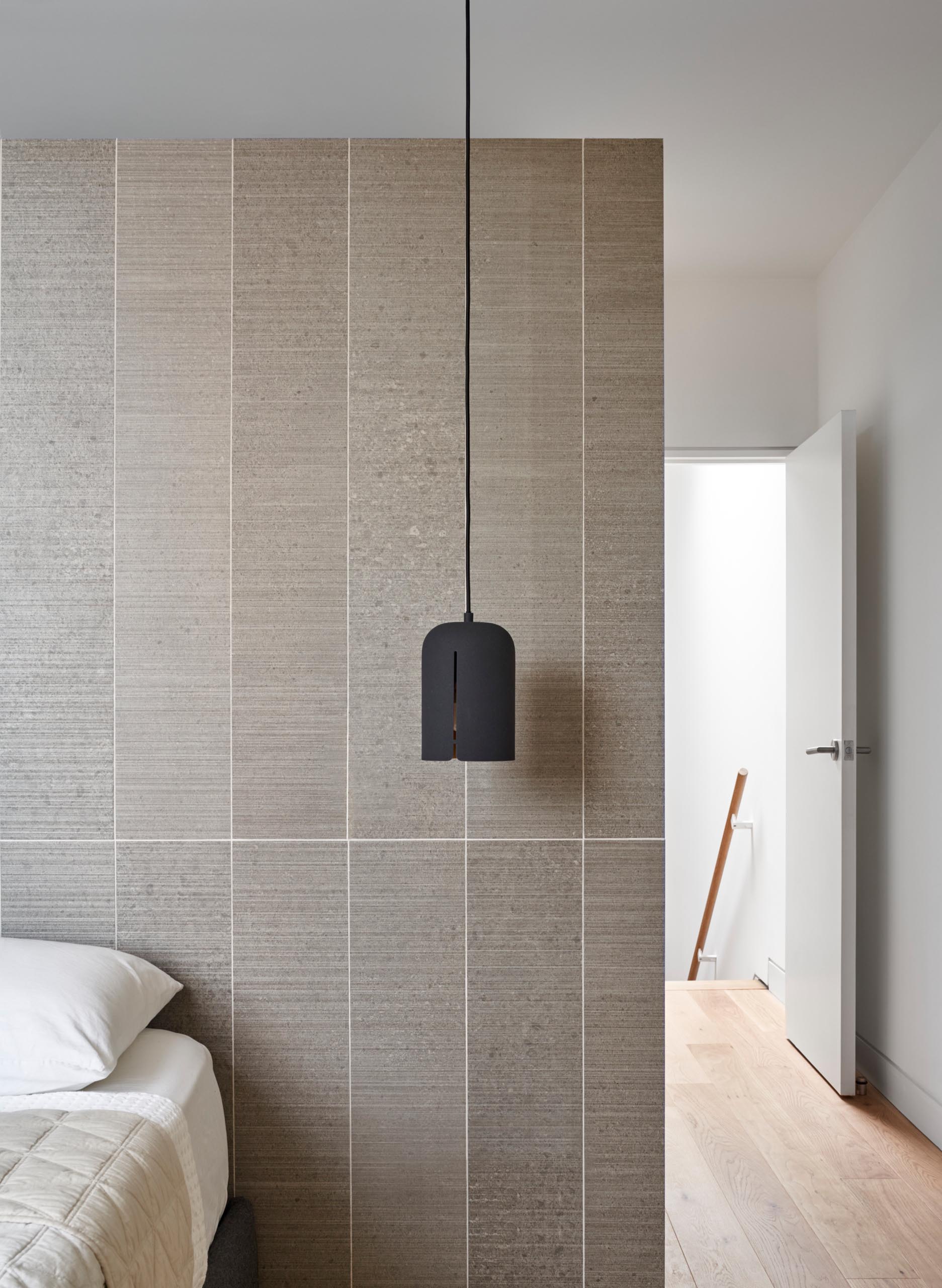 In this bedroom, a matte black pendant light contrasts the accent wall behind the bed and acts as a bedside lamp.