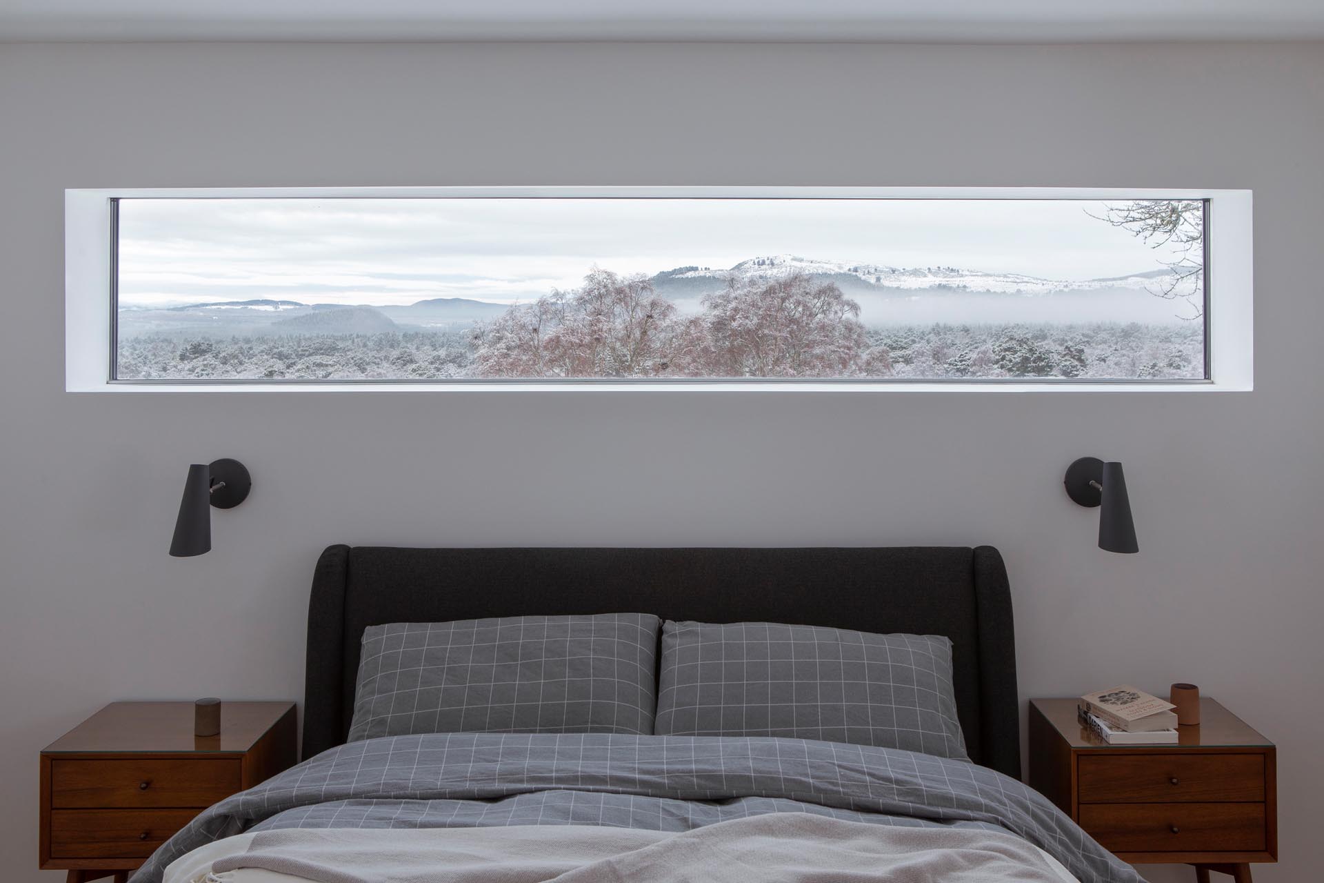 In this modern bedroom, a thin horizontal window removes the need for artwork, as it perfectly frames the view.