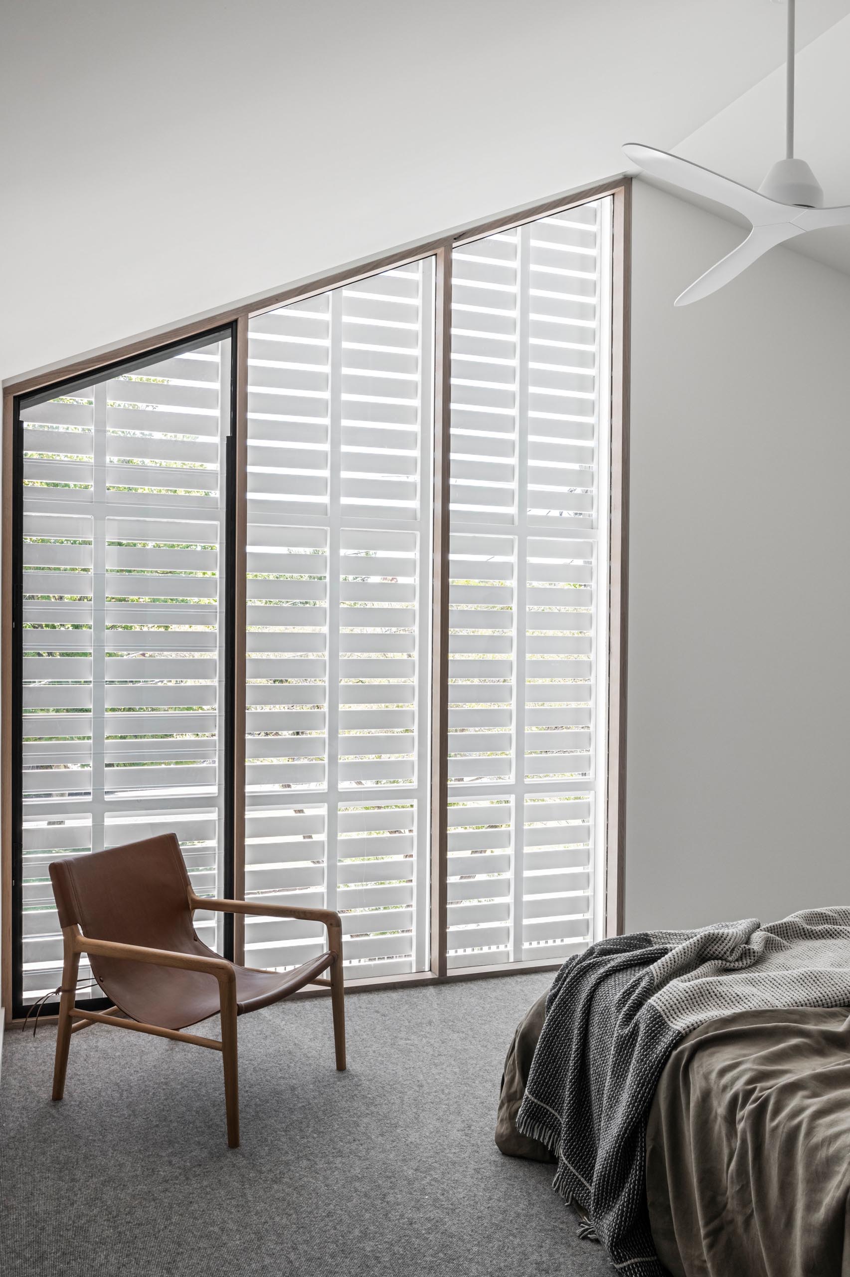 A modern bedroom with exterior shutters that can open to provide street views, or closed for privacy.