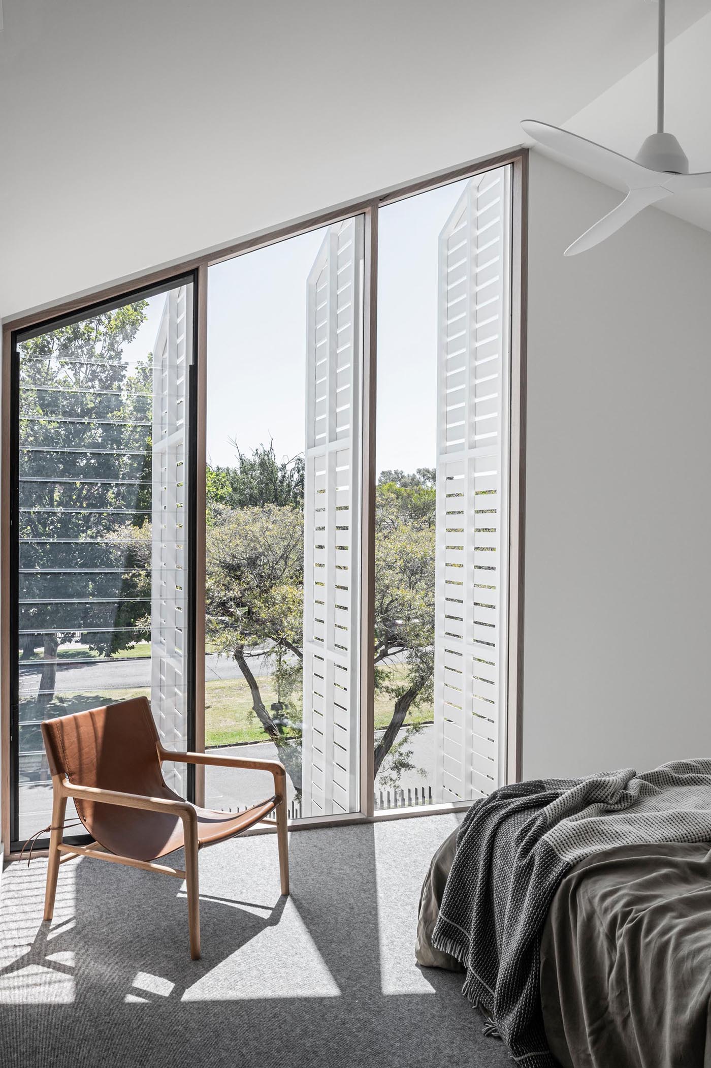 A modern bedroom with exterior shutters that can open to provide street views, or closed for privacy.