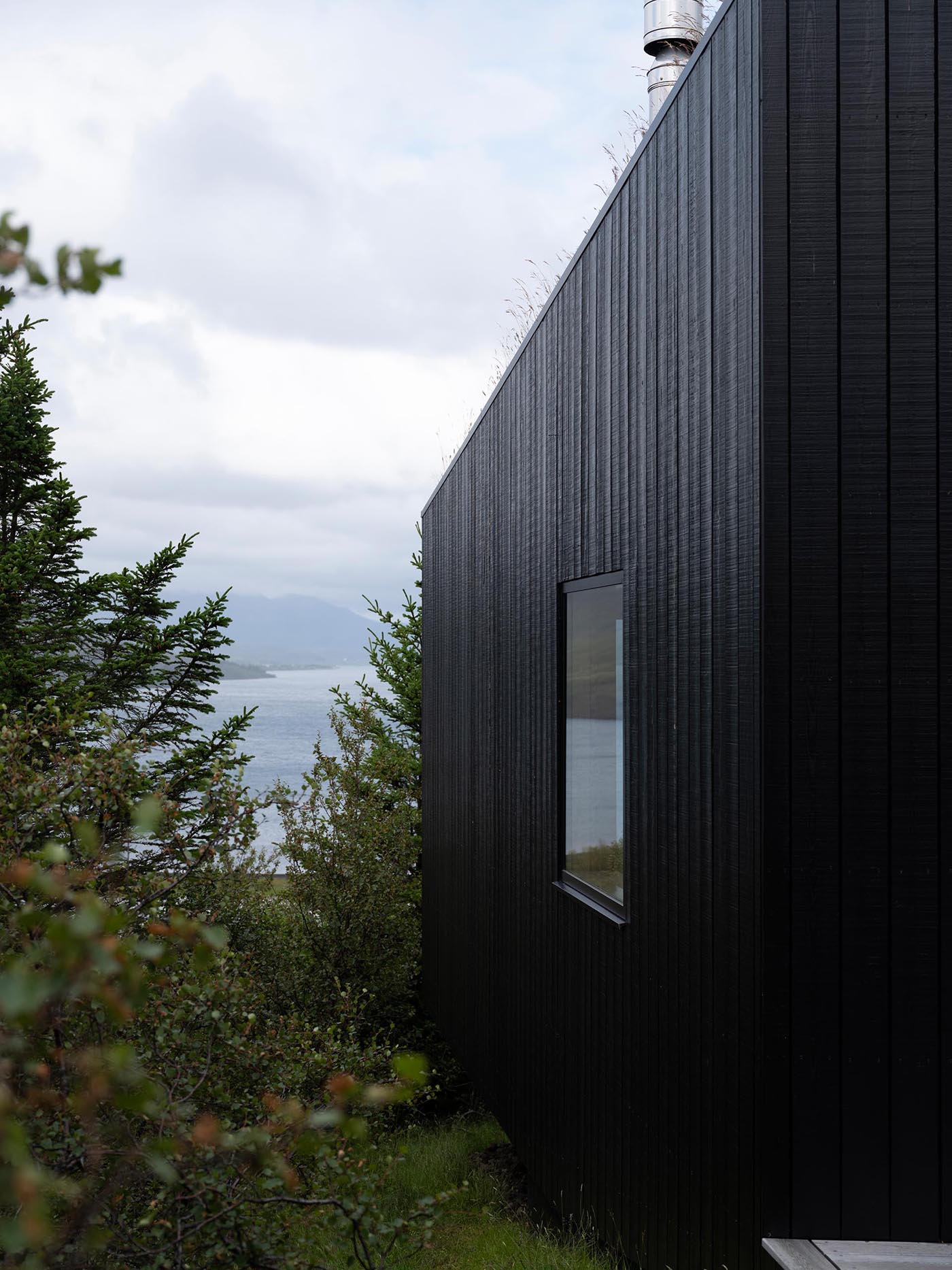 A modern home clad in blackened wood siding.