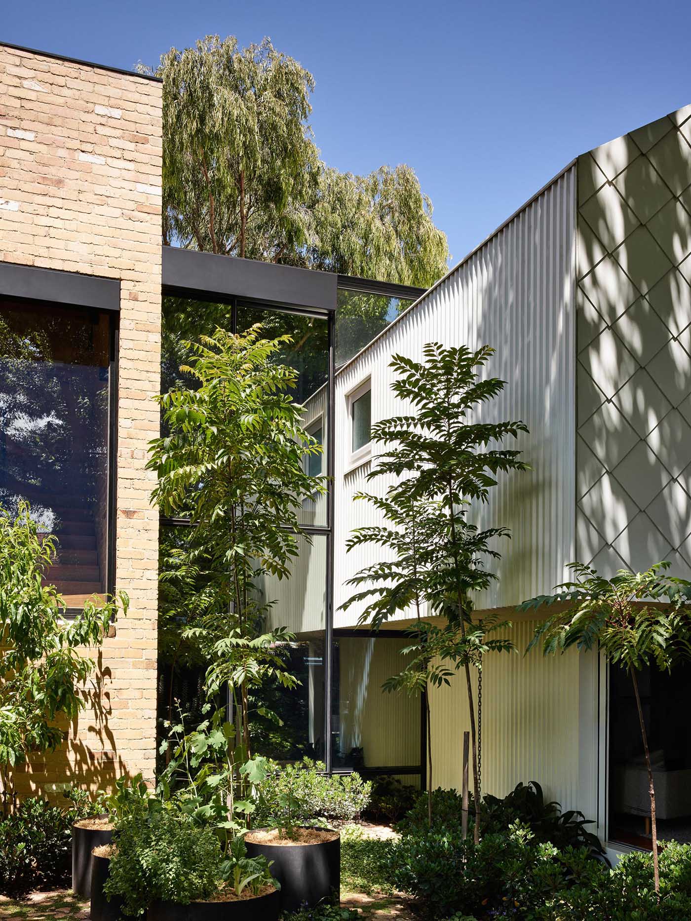 A modern home with indoor/outdoor living spaces, has been built using recycled yellow brick and metal shingles.