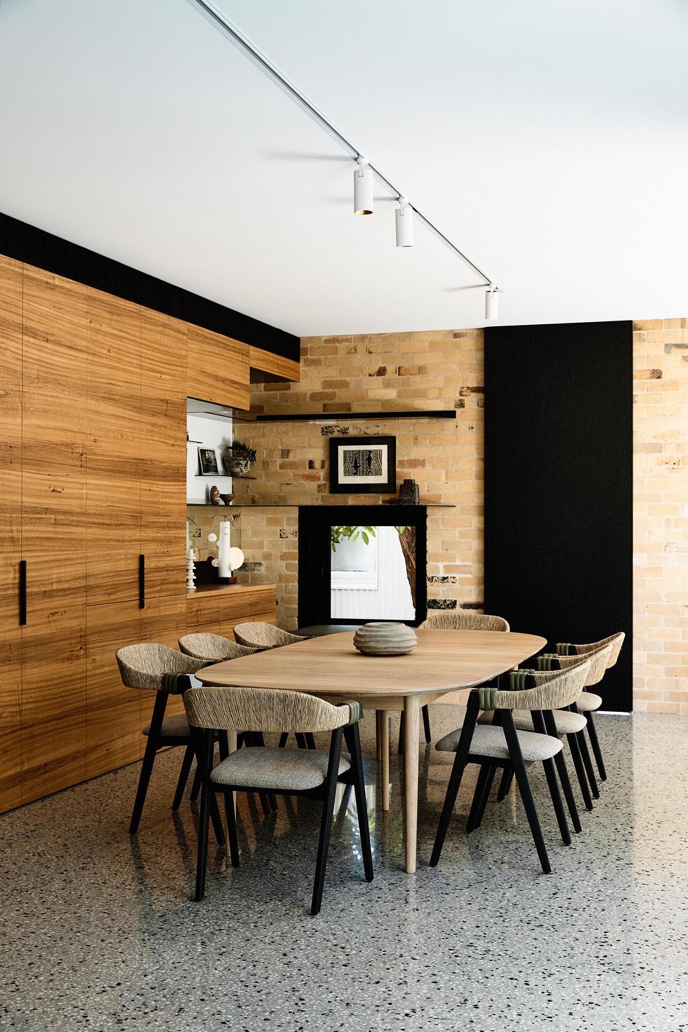 The wood cabinets from the kitchen continue through to this dining room, and result in an open niche with shelving. Beside the cabinets and in the brick wall, there's a small built-in window seat.