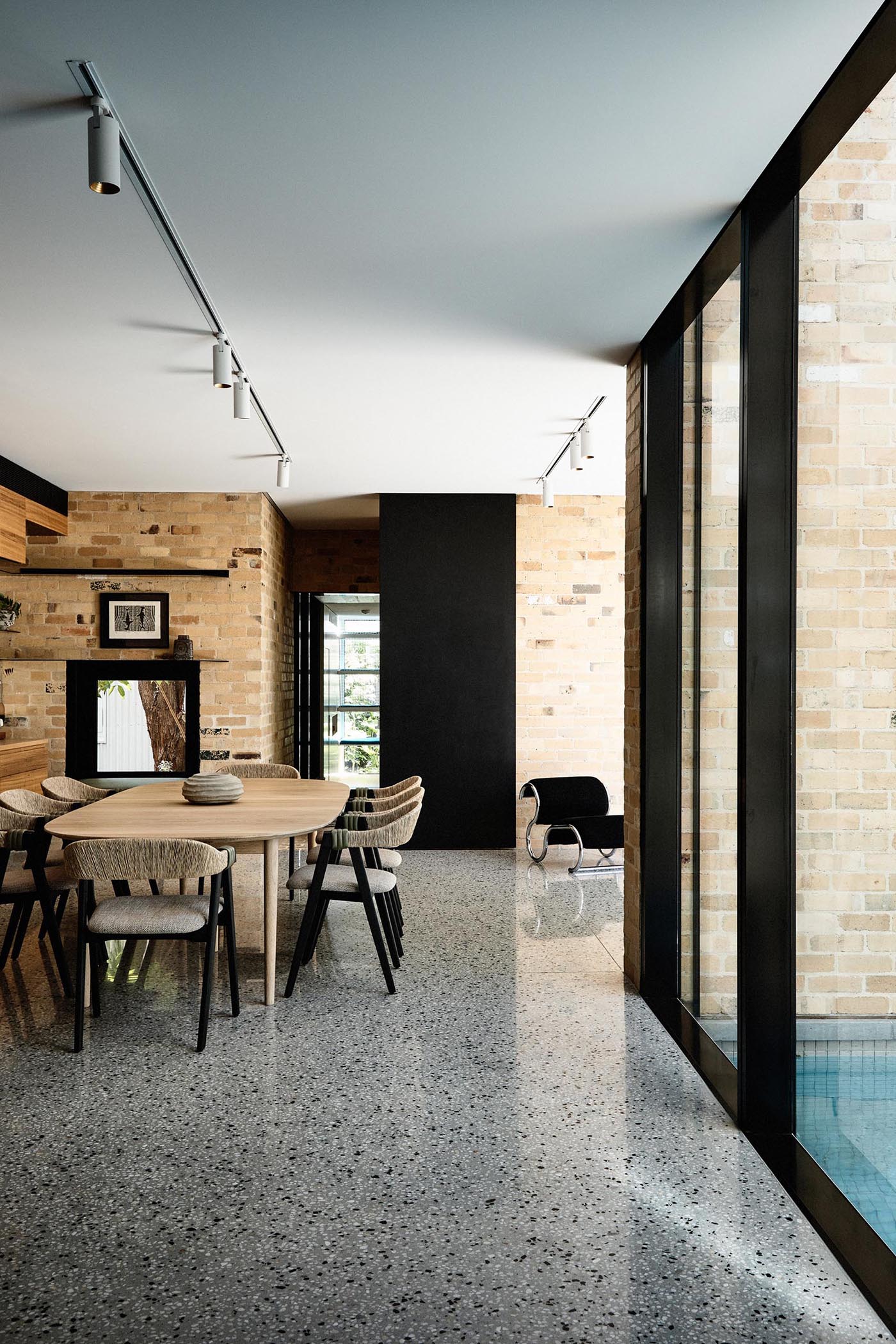 A modern dining room with brick walls and a wood table.