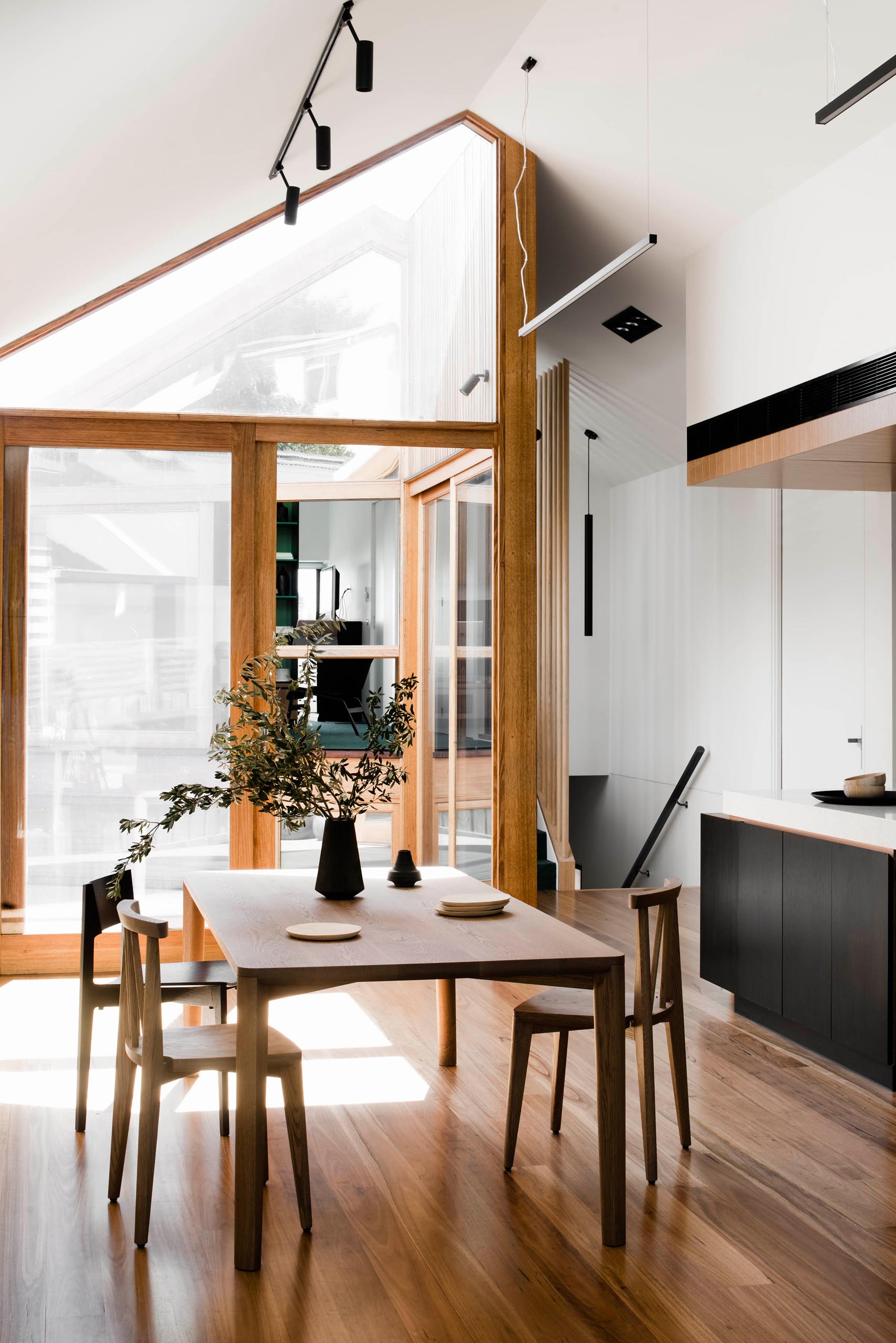 Inside this modern home, wood framed windows and doors, as well as the wood flooring, add a natural element to the mostly white interior.