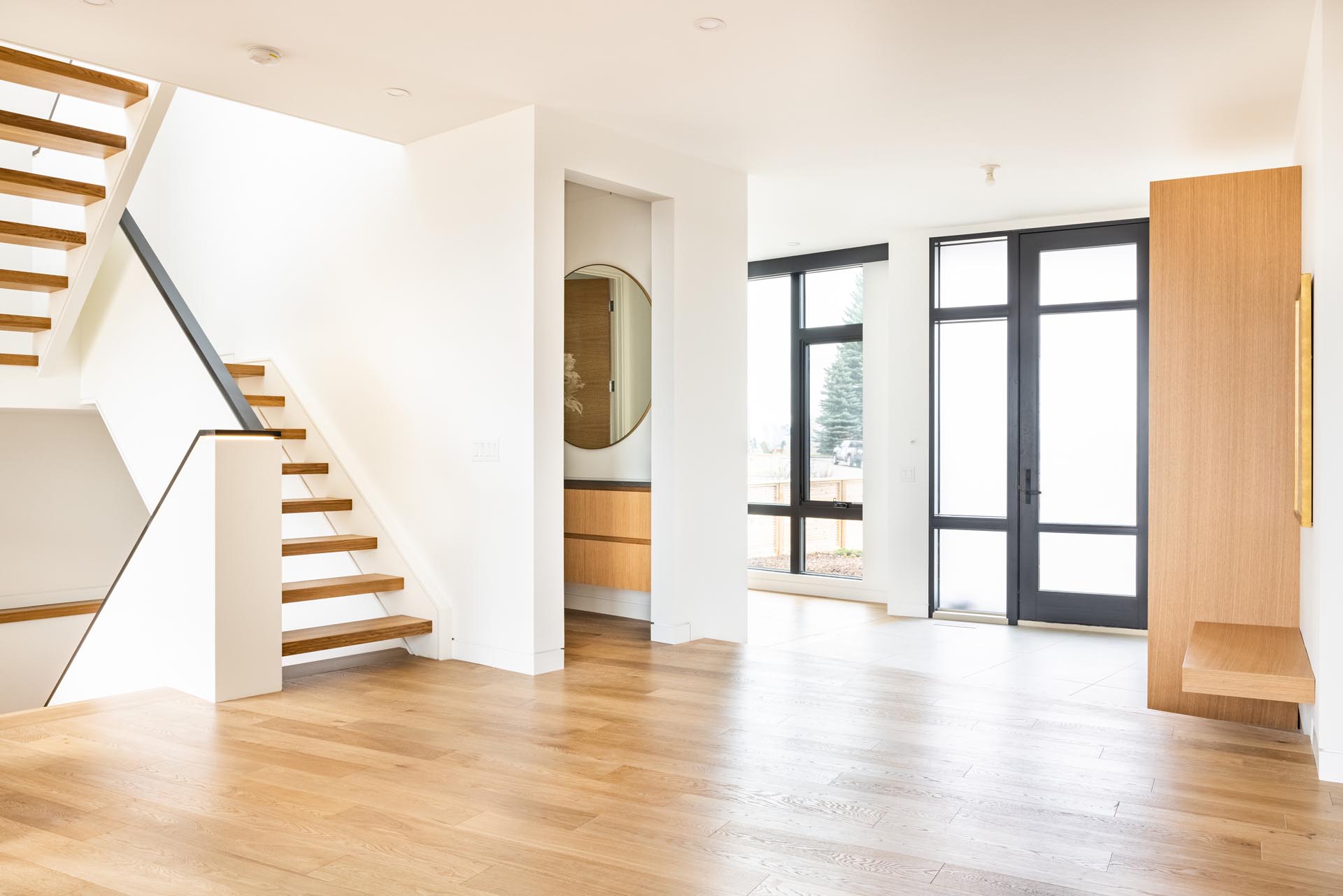 An open entryway with a powder room, wood floors, and a small floating bench.