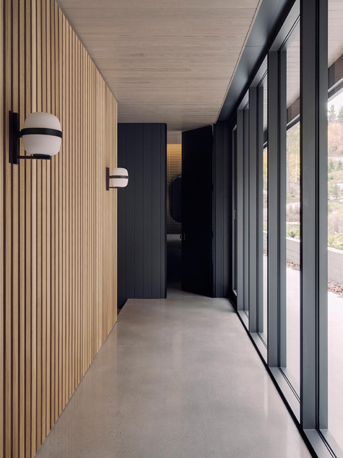 A modern hallway with a wood slat wall and floor-to-ceiling windows.