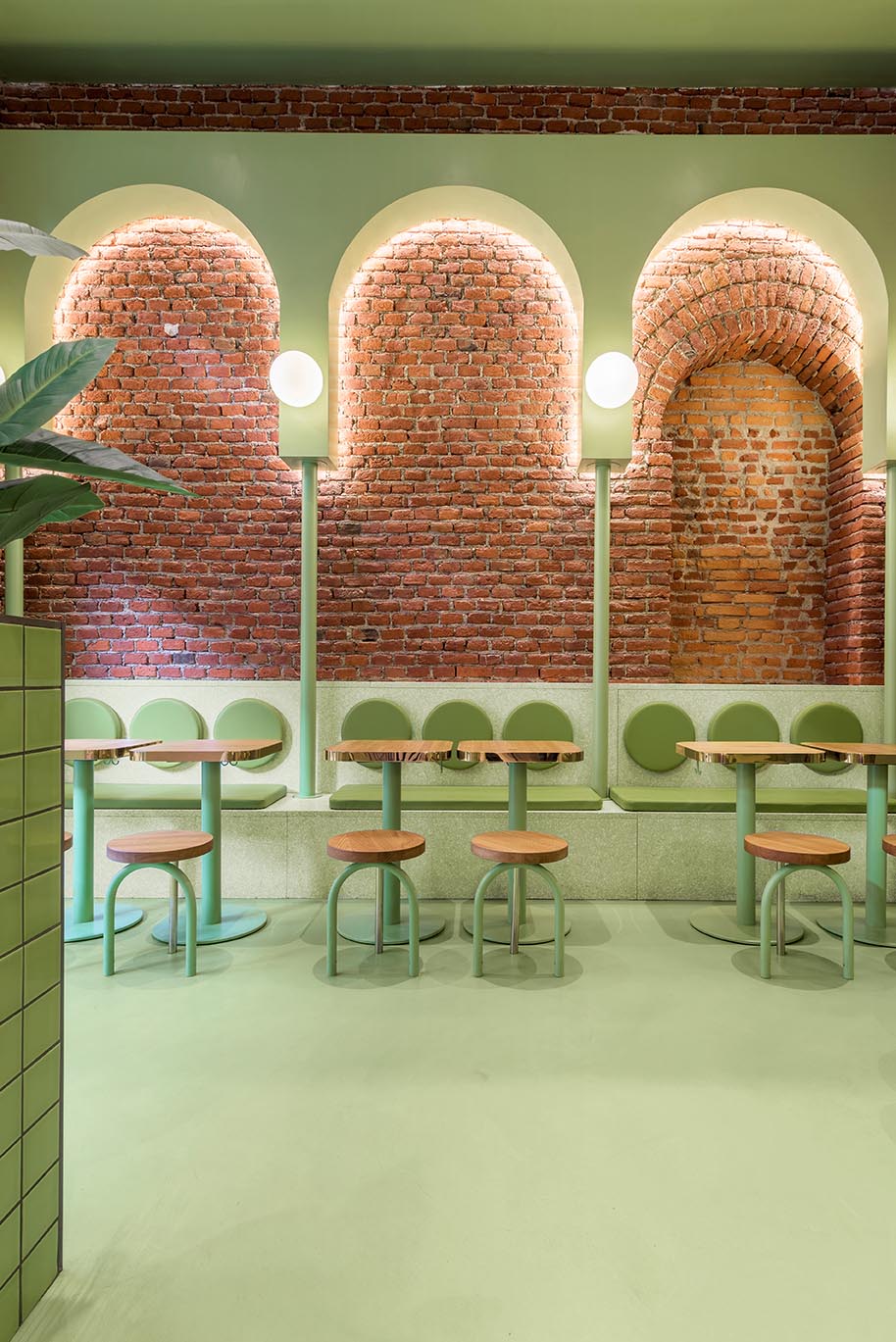 A new restaurant has brick walls and green interior design elements.