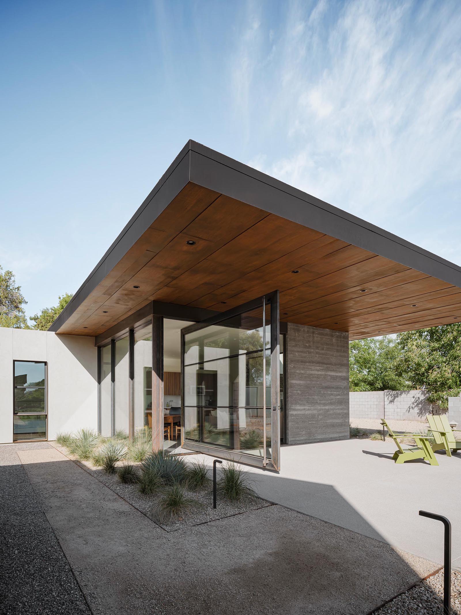 The 12 foot wide pivoting glass door of this small and modern home connects the interior spaces to the patio.