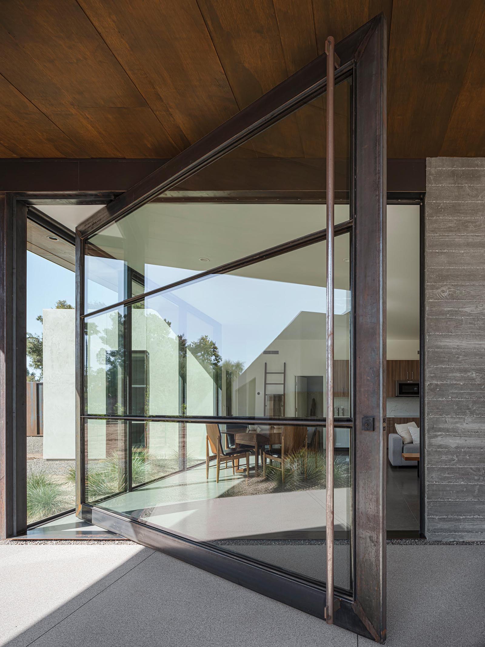 A modern oversized pivoting glass door with a metal frame.