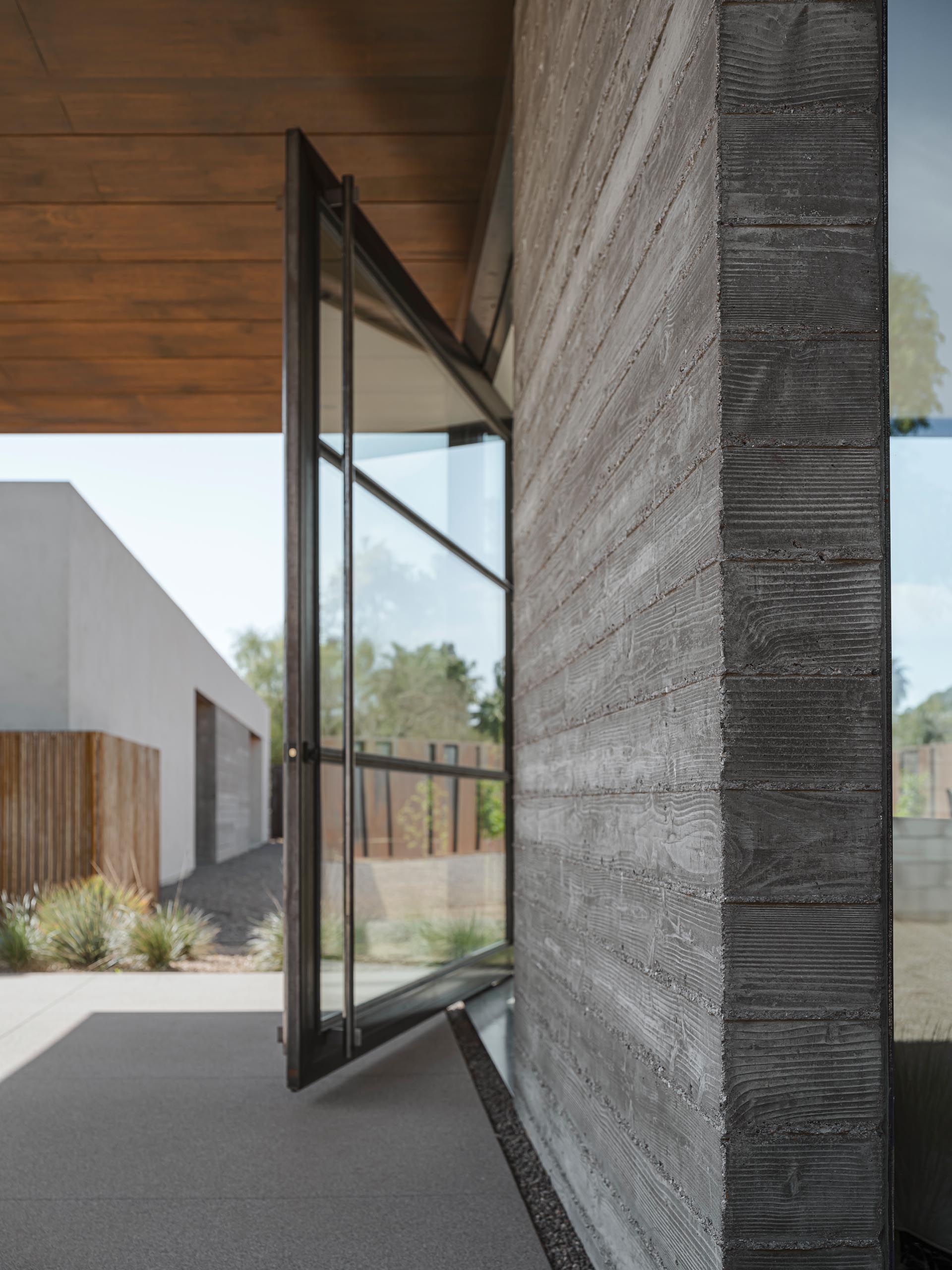 A modern oversized pivoting glass door with a metal frame.