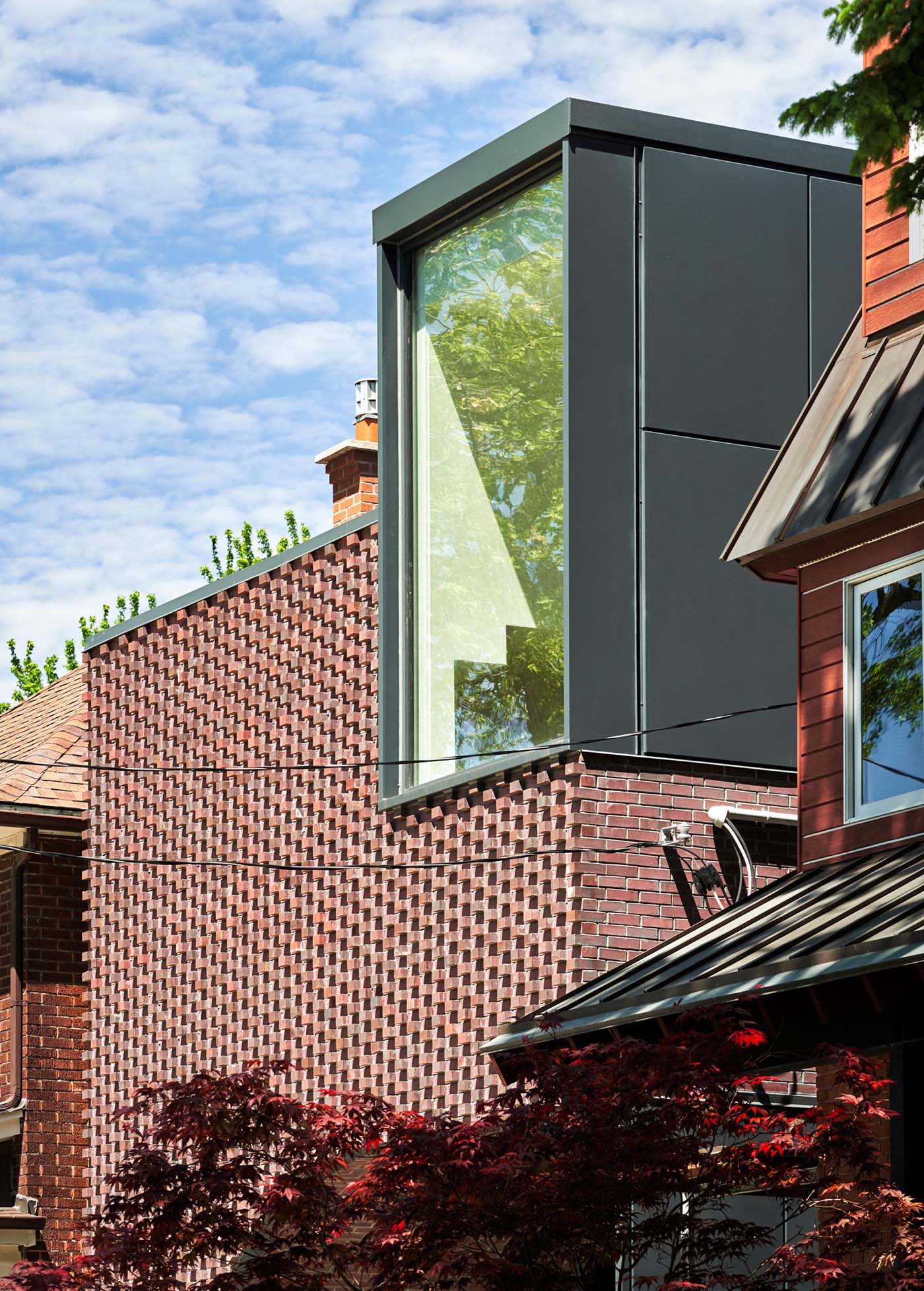 In the summer, the brick protrusions on this modern home texture the facade with stark shadows, and in the winter the texture transforms through bricks creating shelves for the snow to fall on.