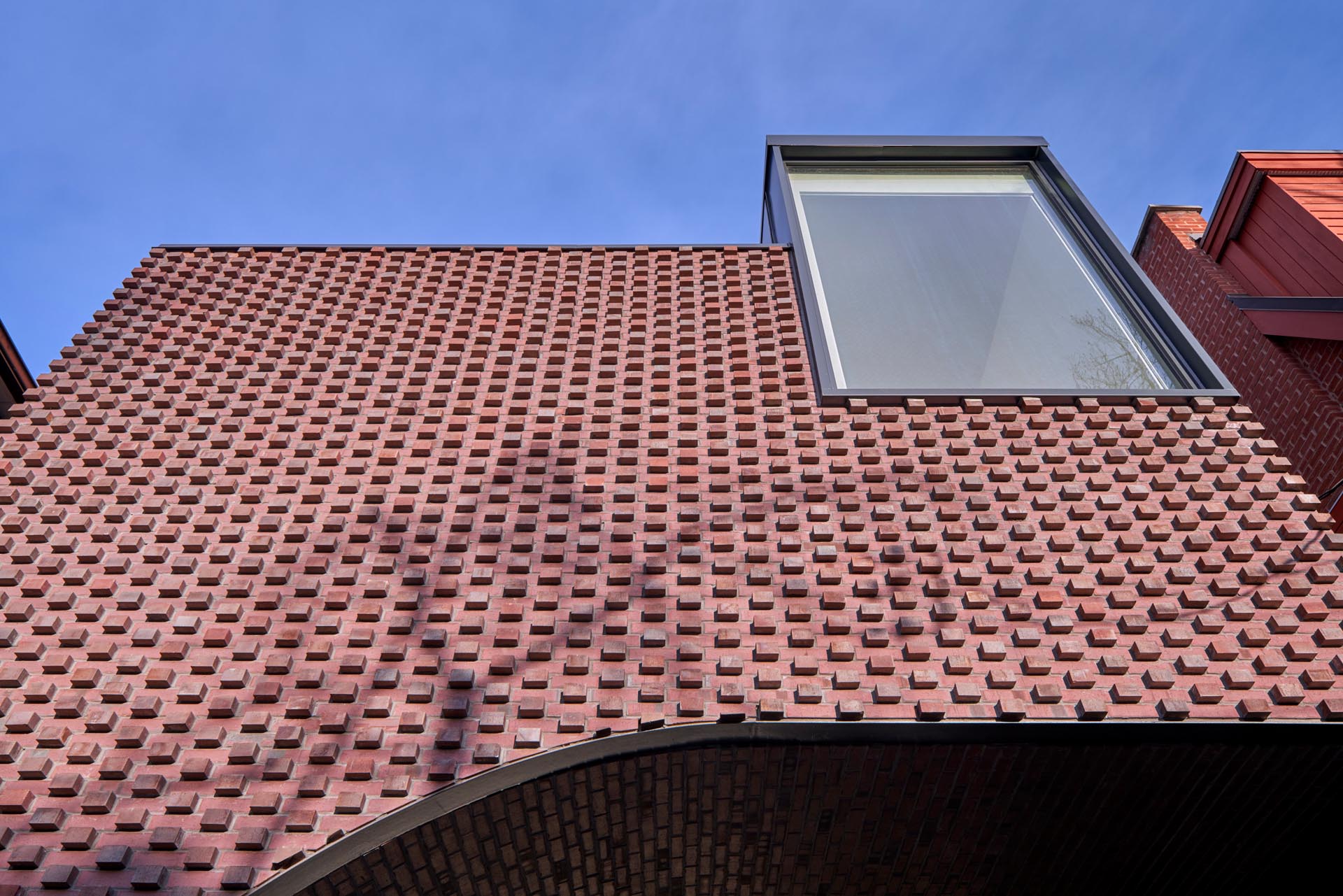 In the summer, the brick protrusions on this modern home texture the facade with stark shadows, and in the winter the texture transforms through bricks creating shelves for the snow to fall on.