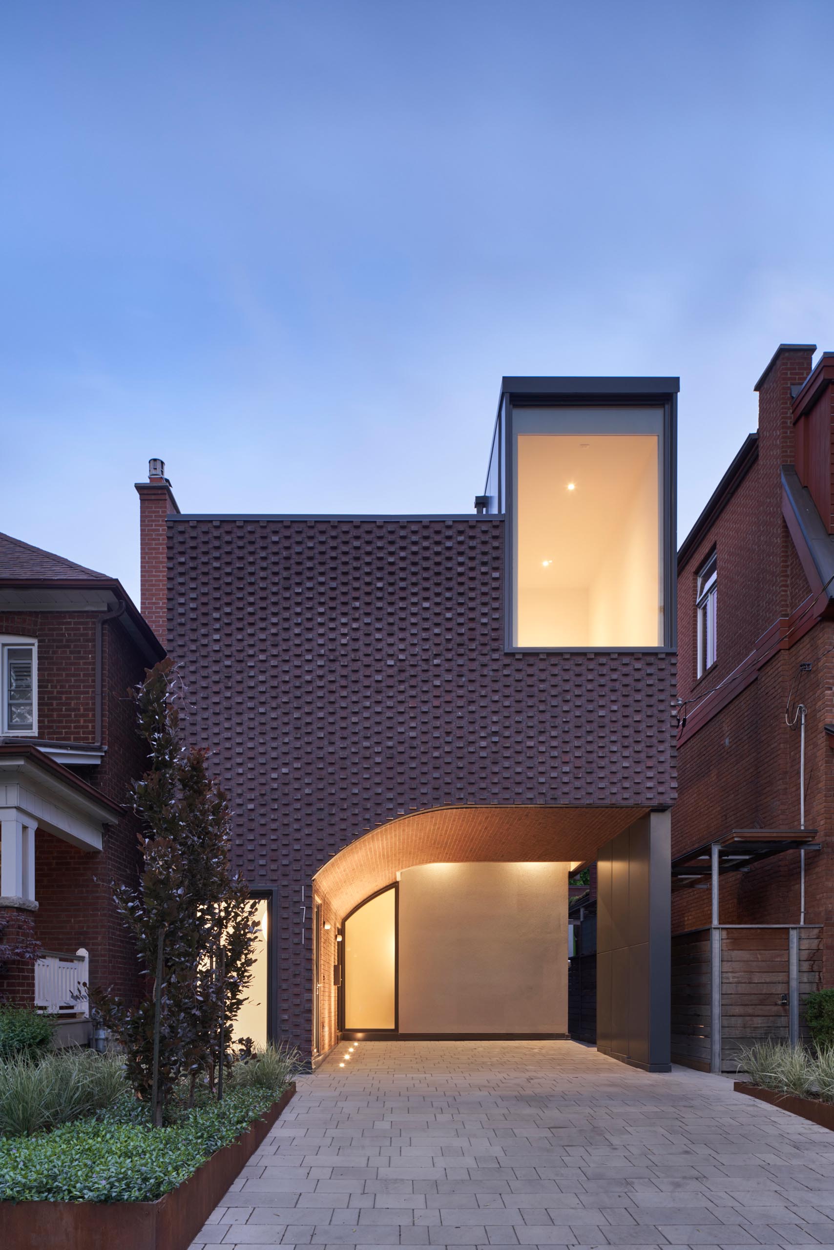 At dusk, the lights from the interior of the home and the featured exterior lighting highlight the windows and doors, and create a soft ambient glow.