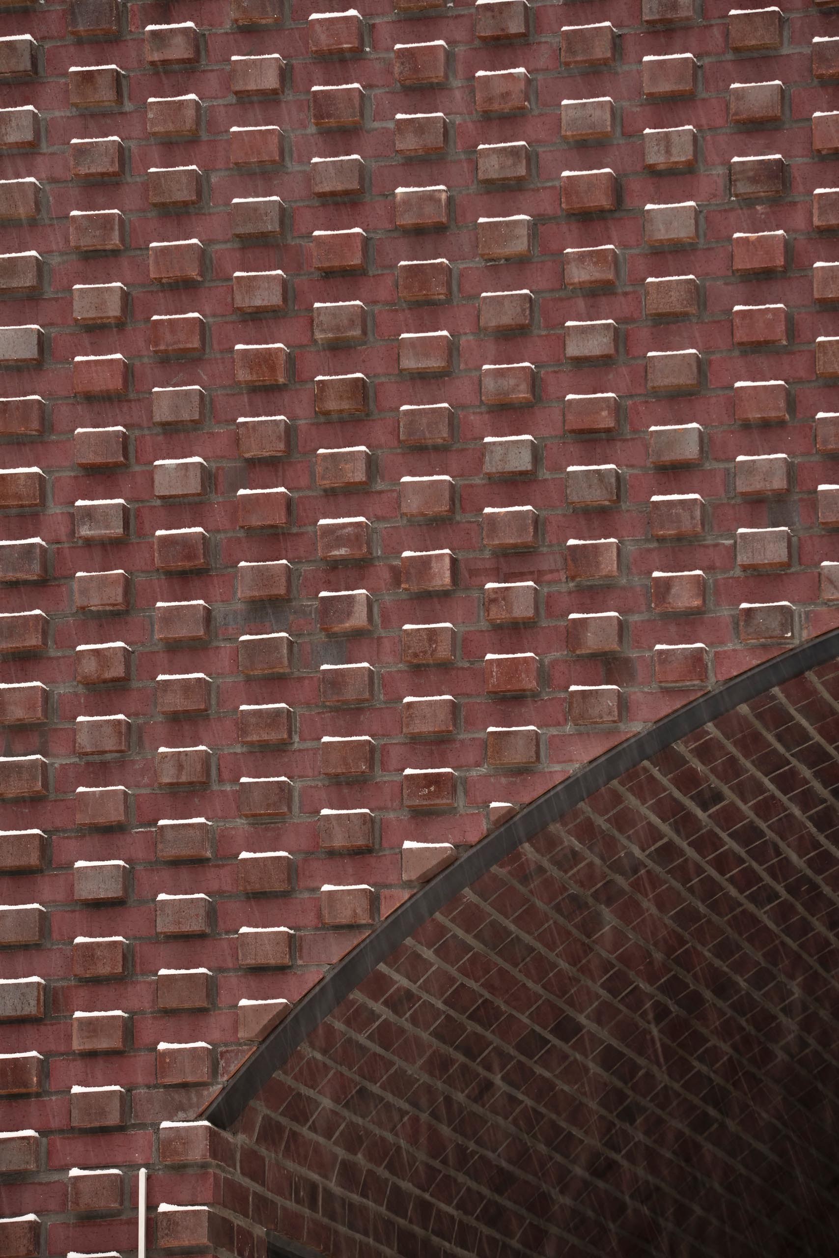 In the summer, the brick protrusions texture the facade with stark shadows, and in the winter the texture transforms through bricks creating shelves for the snow to fall on.