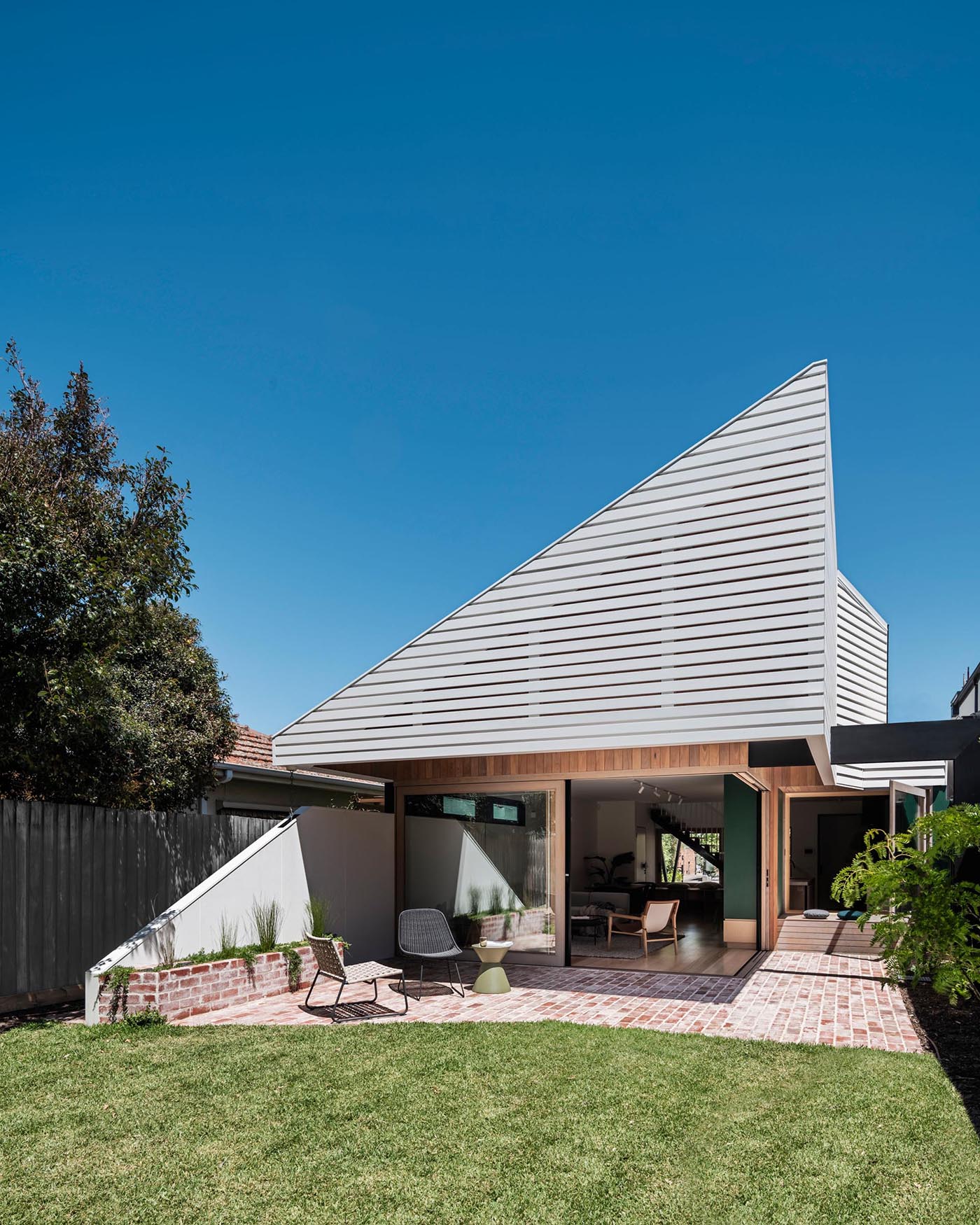 A modern home with a partially shaded brick patio.