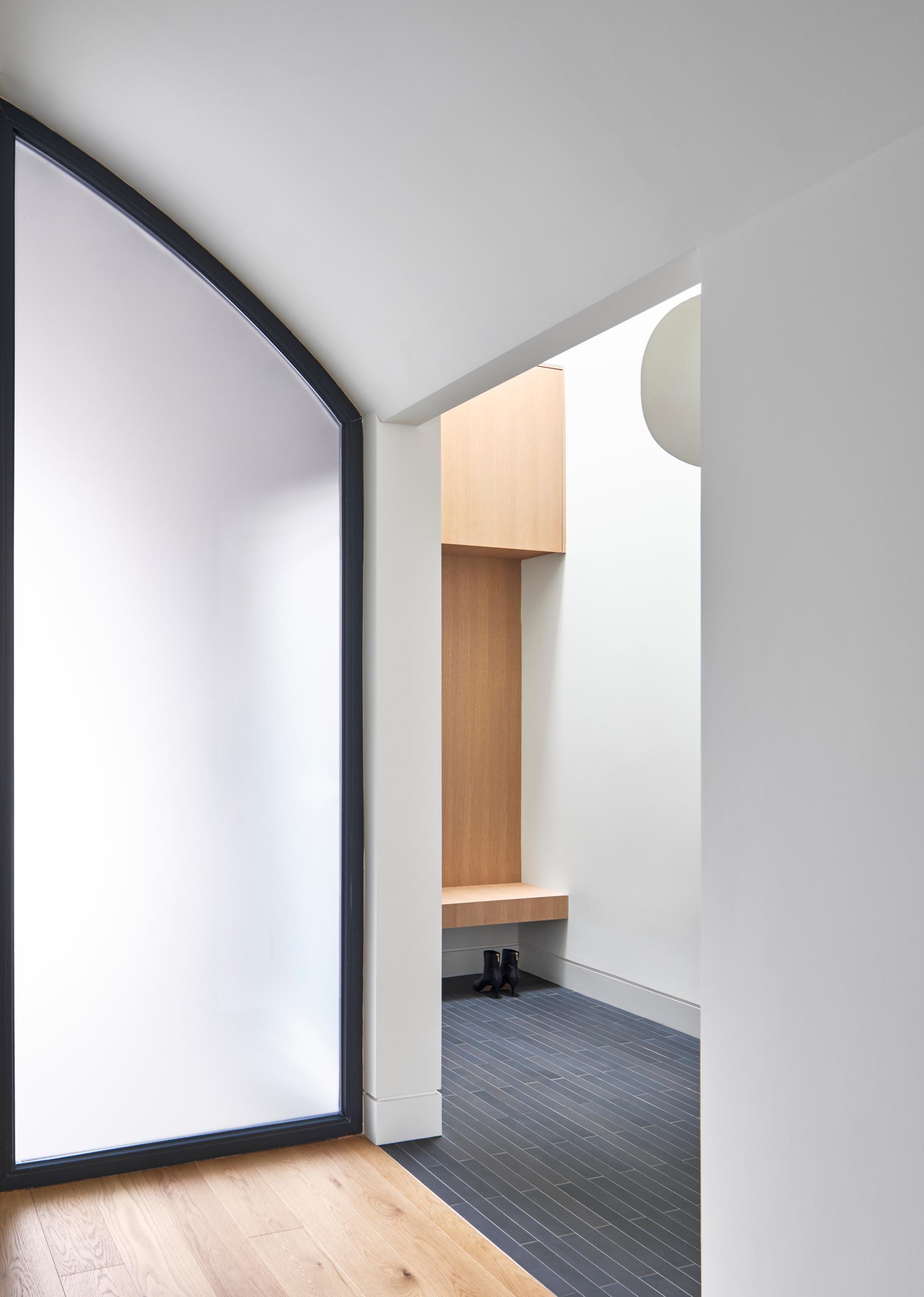 Inside this modern home, there's a small entryway with a bench for taking off shoes and coats.