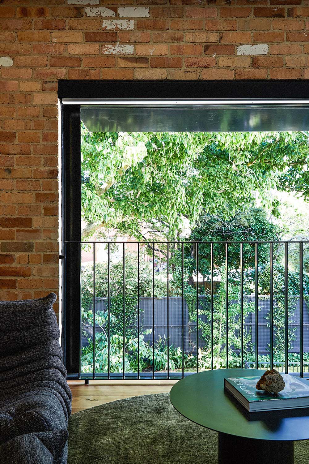 A sitting room furnished with a black sofa that matches the window frames.