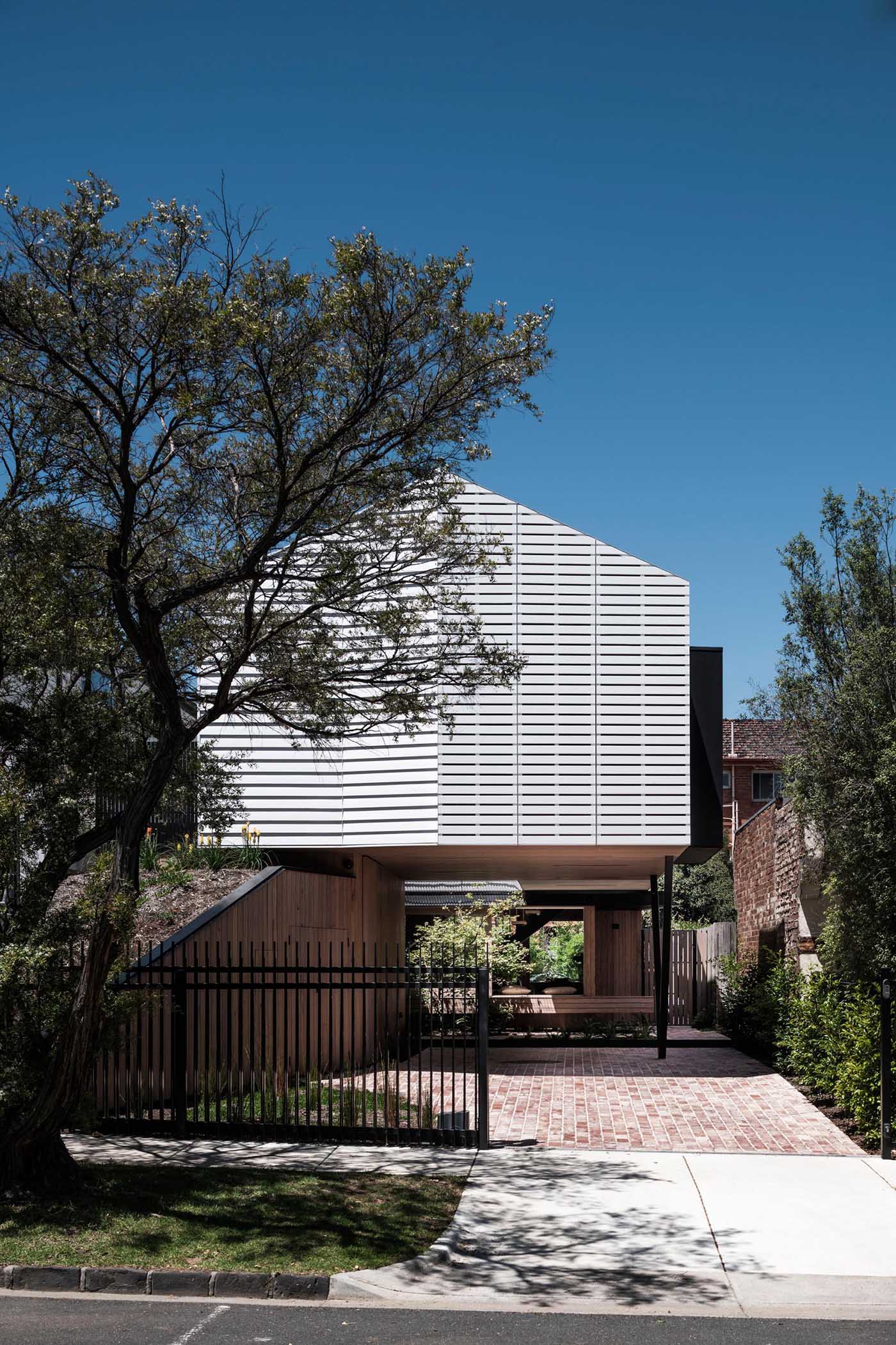 A modern home with a white exterior incorporates mechanically operated shutters that seamlessly match the siding on the house.