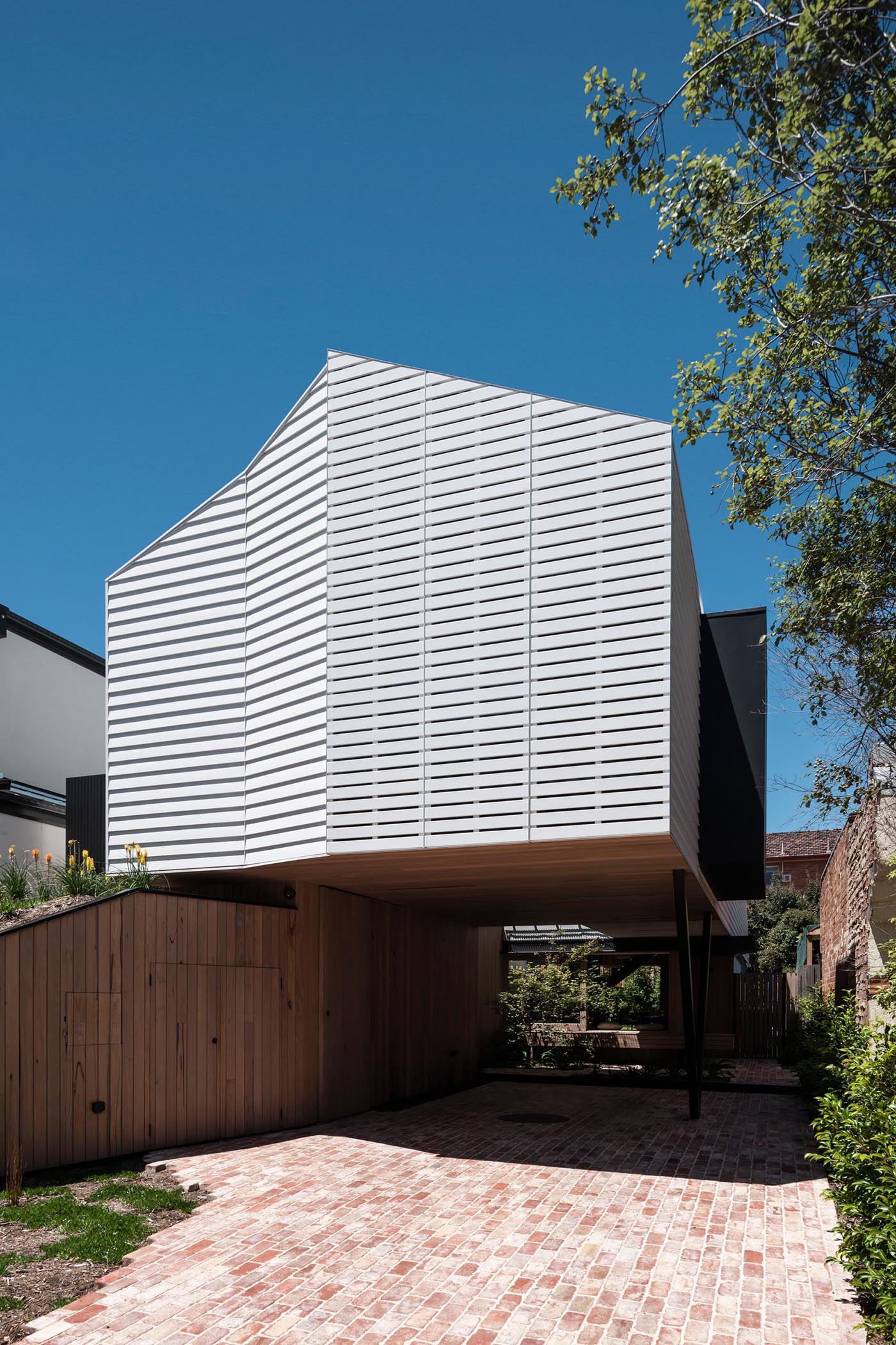 A modern home with a white exterior incorporates mechanically operated shutters that seamlessly match the siding on the house.