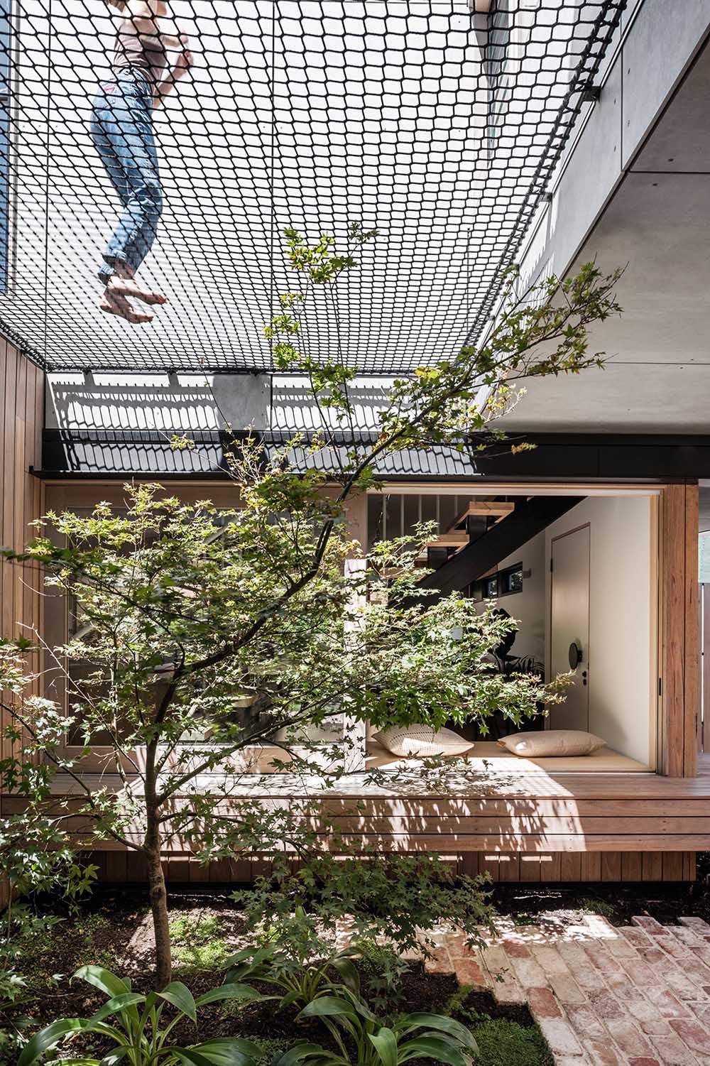 A small courtyard with bricks, plants, and a net for relaxing above.